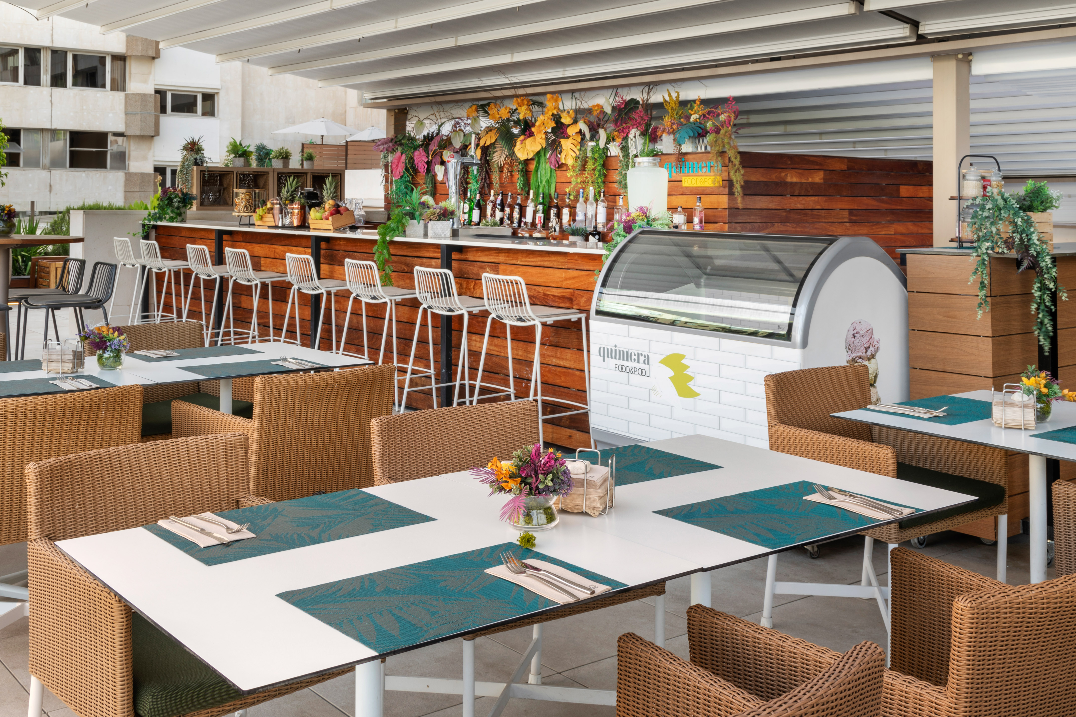 Vibrant outdoor restaurant patio with bar, wicker chairs, and tropical decor.