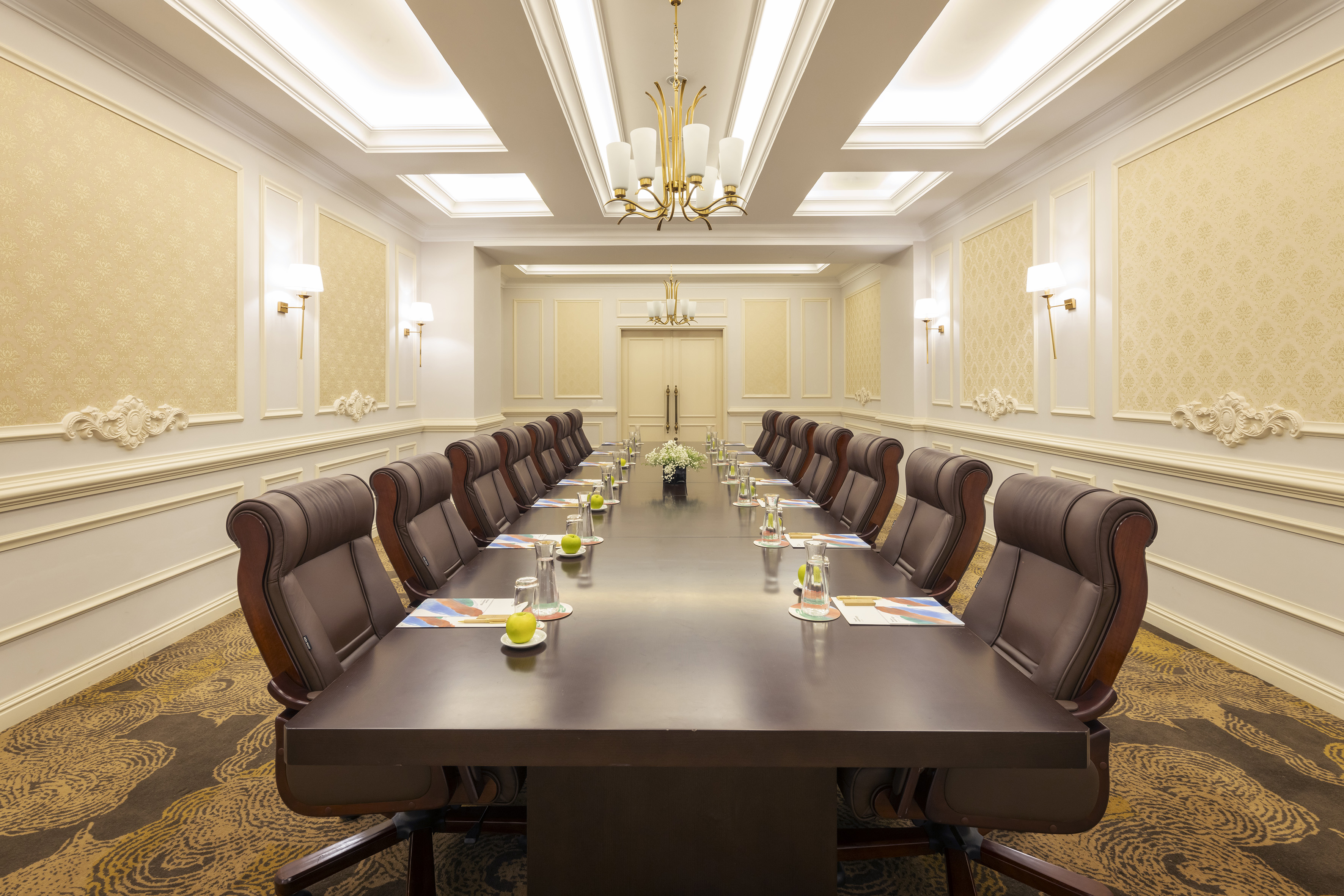 Elegant boardroom with long table, executive chairs, and luxurious decor.