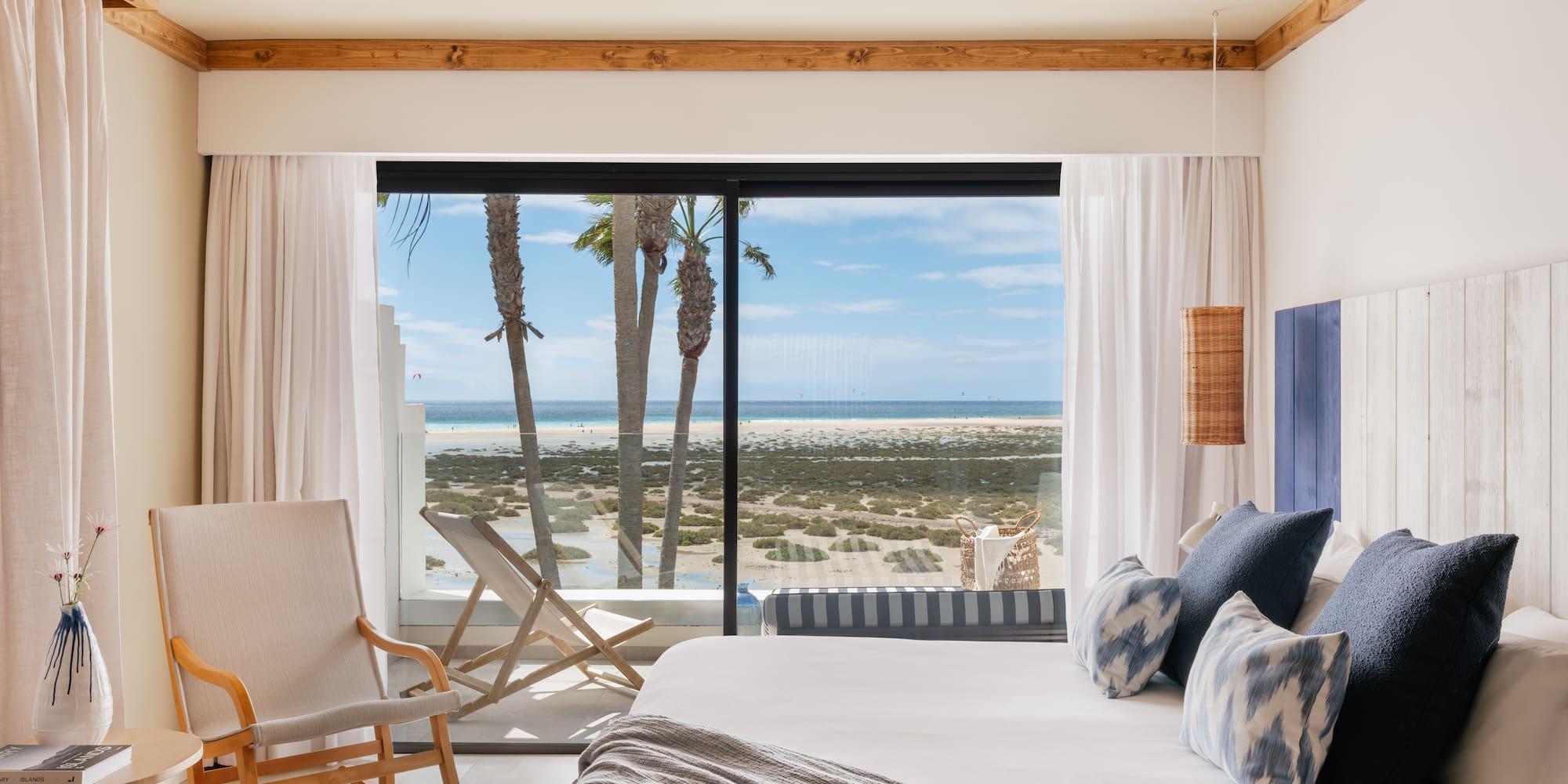Modern oceanfront bedroom with beach view, palm trees, and coastal decor.