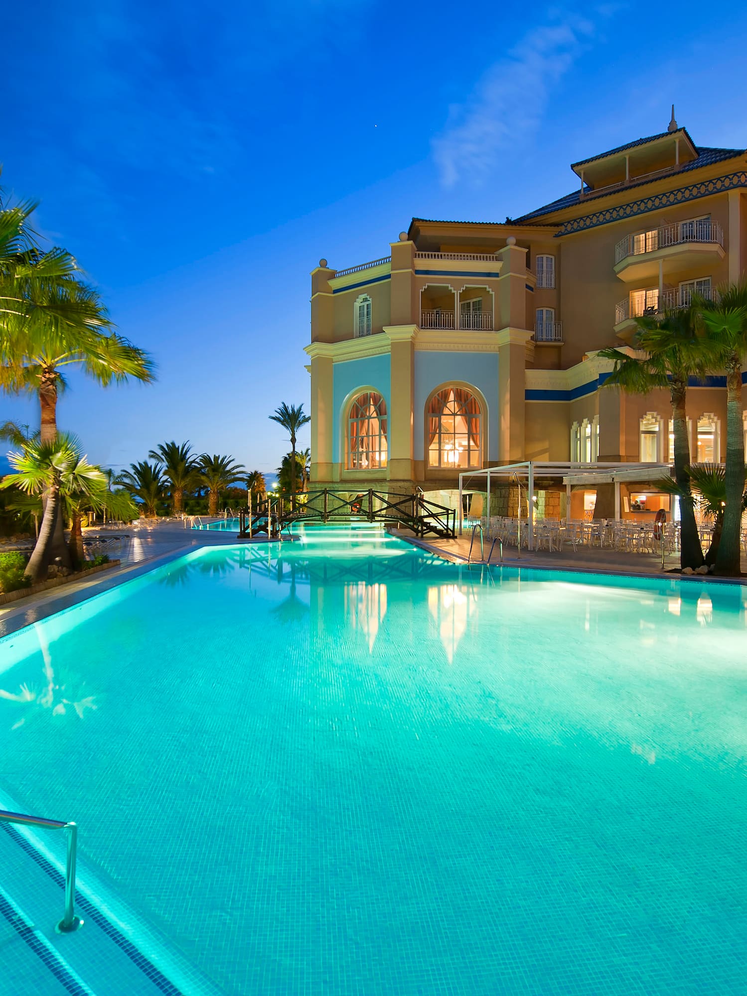 a pool with palm trees and a building
