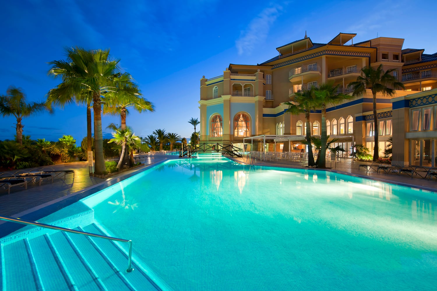 a pool with palm trees and a building