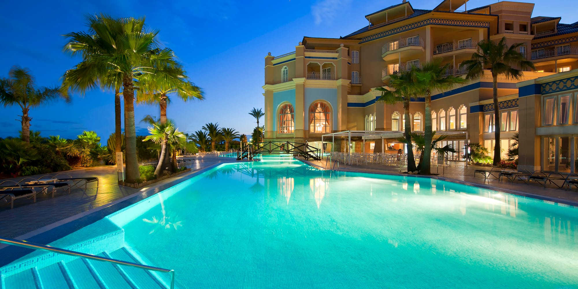 a pool with palm trees and a building