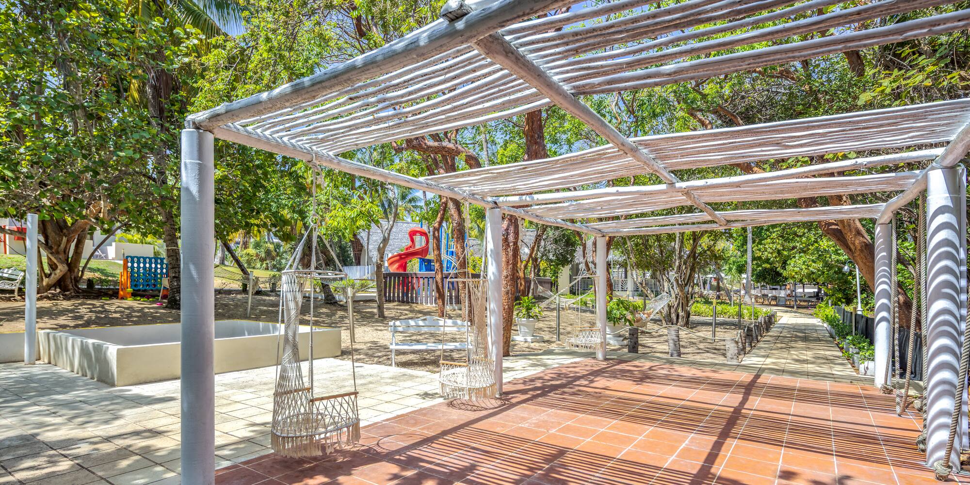 a white structure with swings and trees in the background