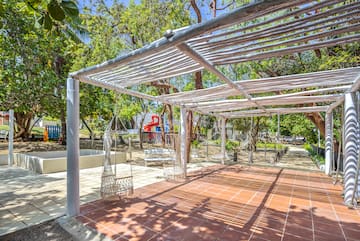a white structure with swings and trees in the background