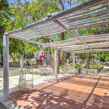 a white structure with swings and trees in the background