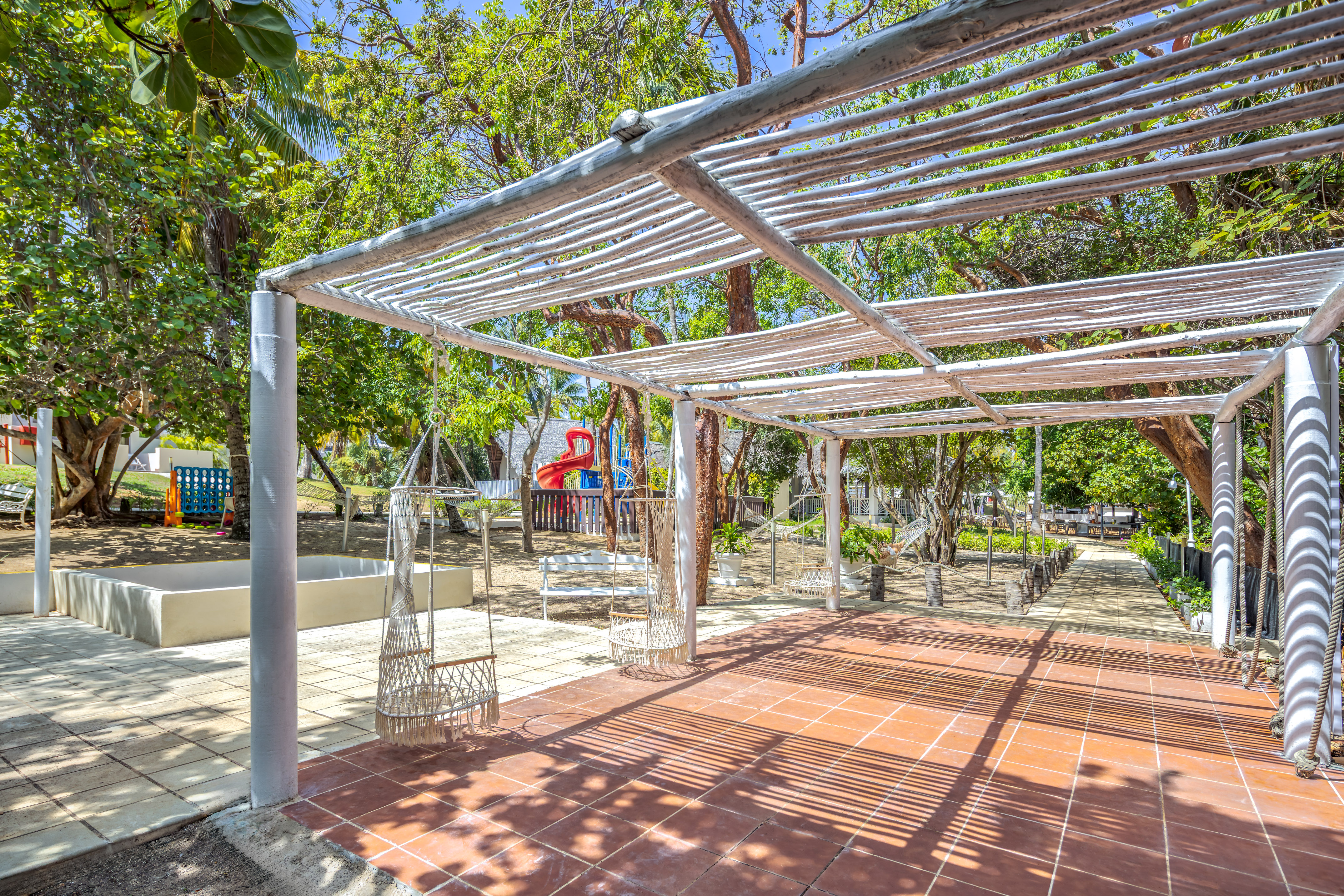 a white structure with swings and trees in the background