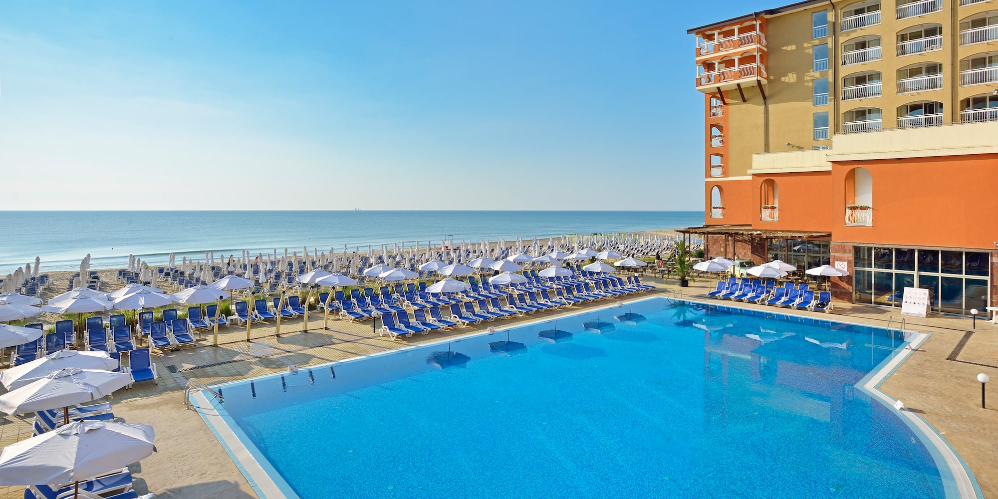 a swimming pool with chairs and umbrellas by a building