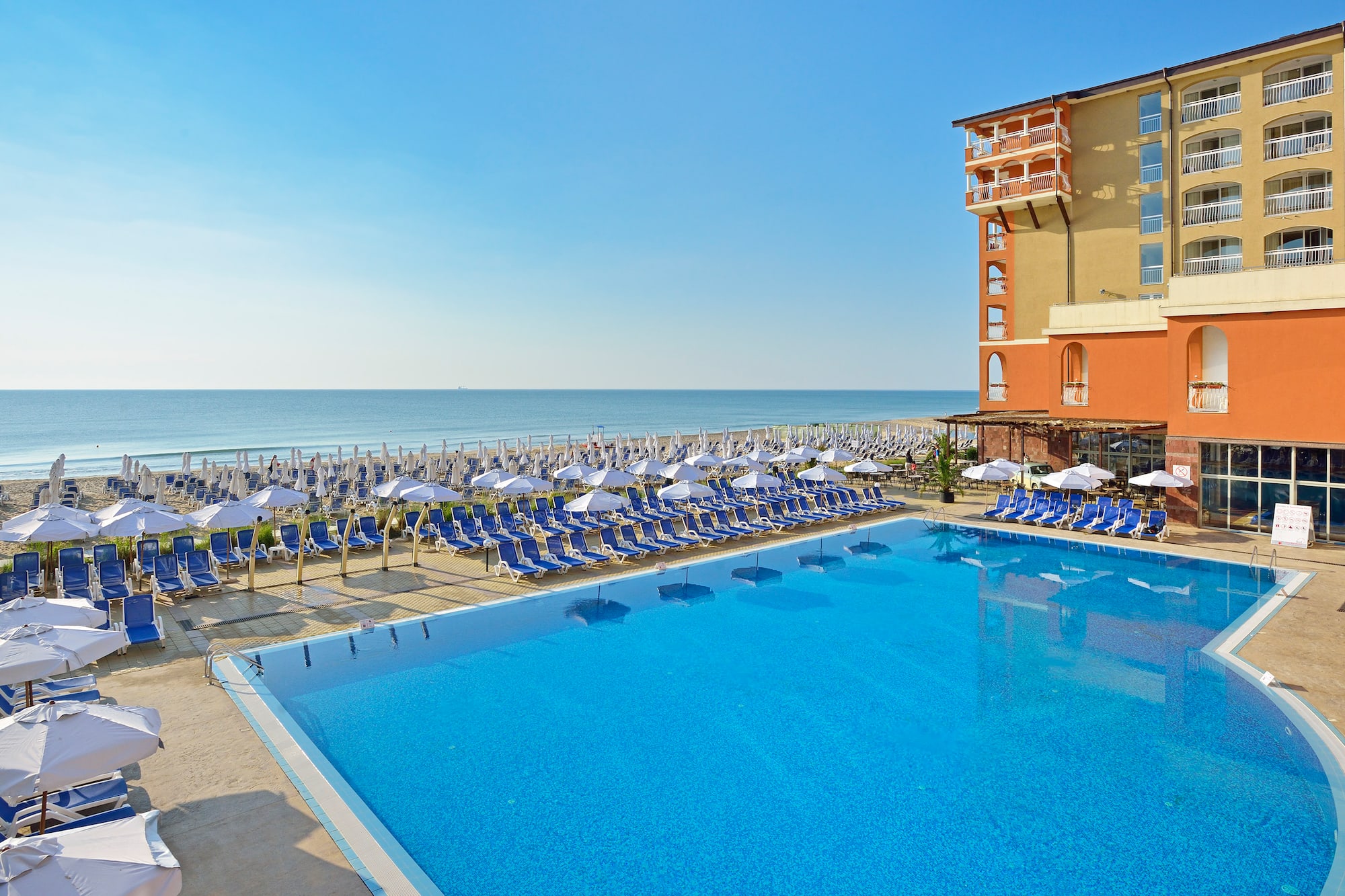a swimming pool with chairs and umbrellas by a building