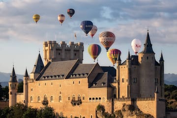 a castle with hot air balloons in the sky