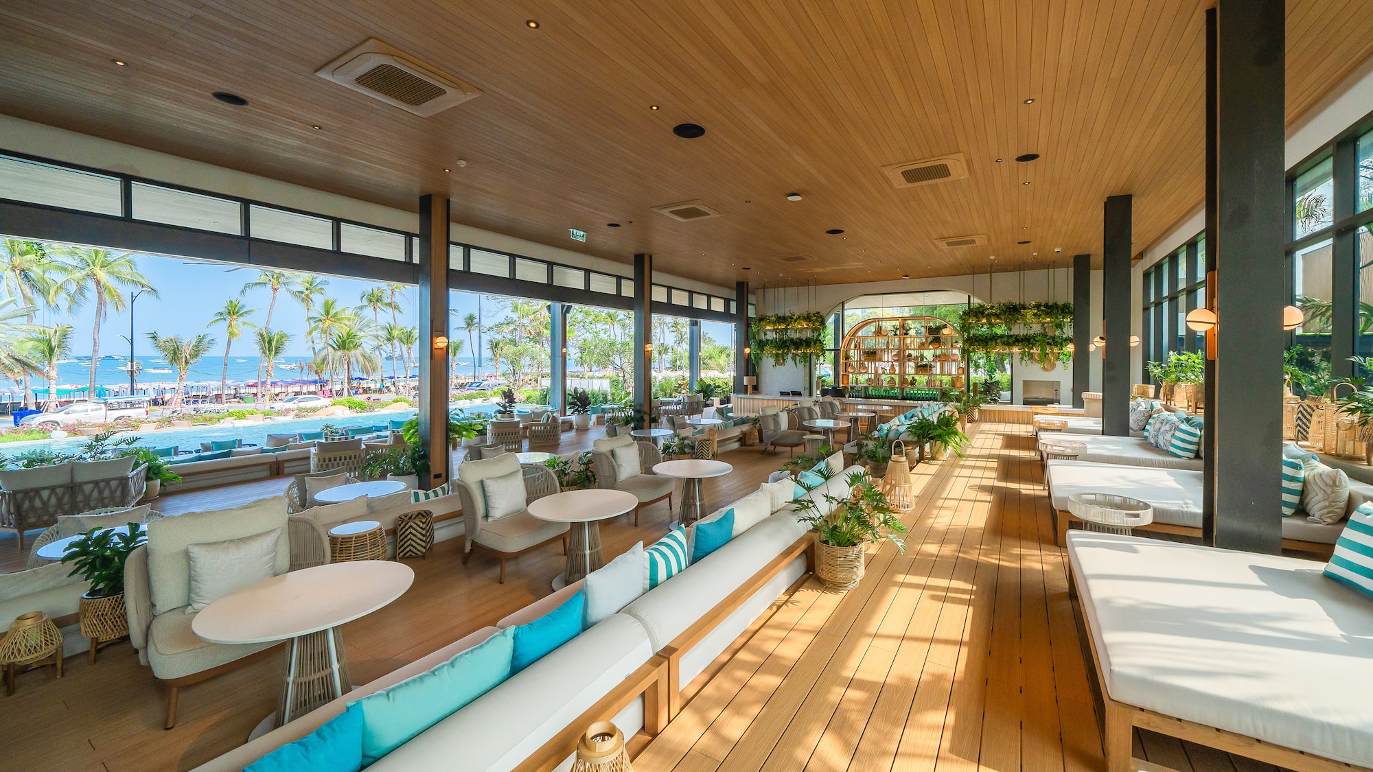 Tropical resort lounge with ocean view, palm trees, and modern decor.