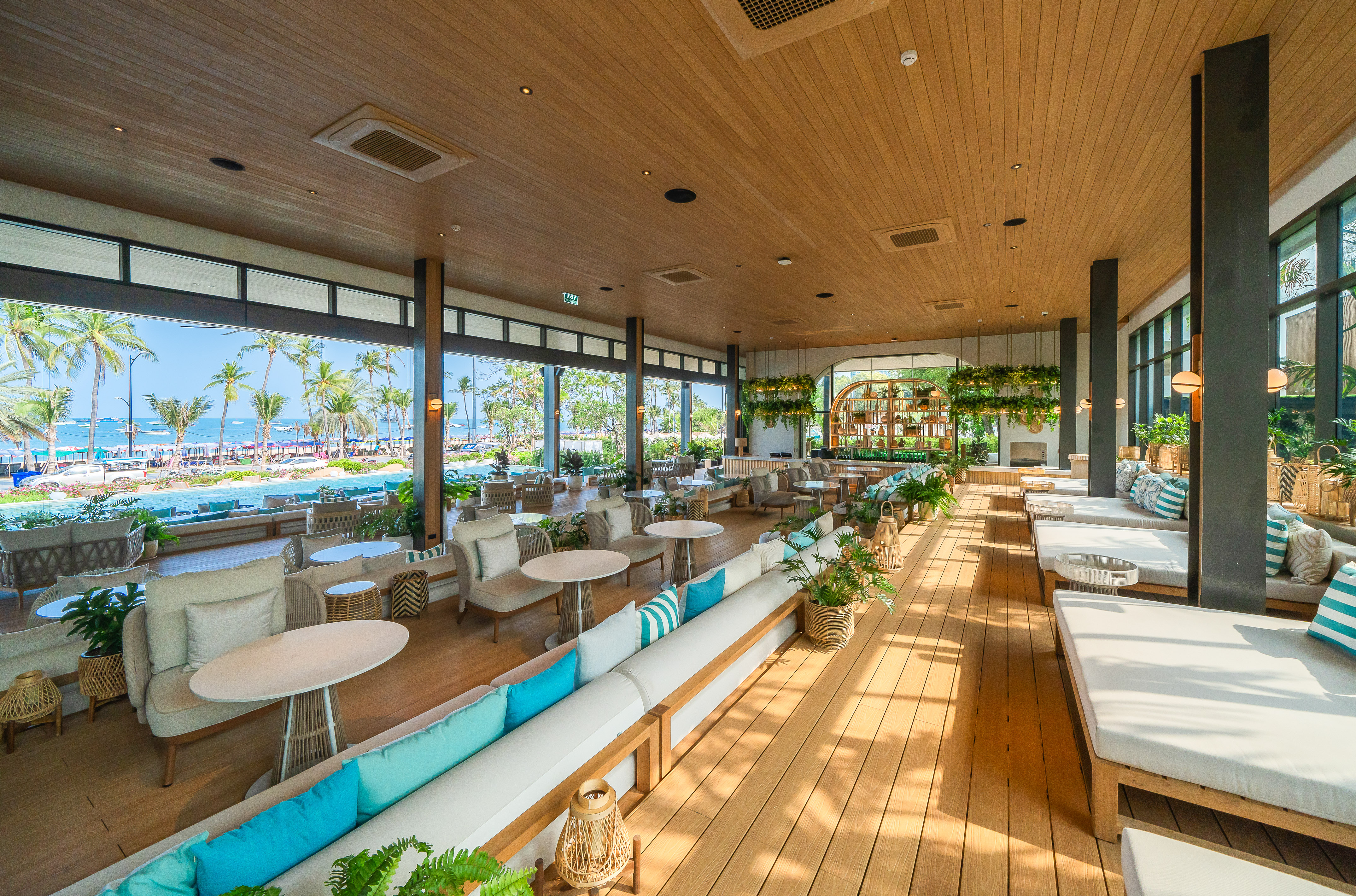 Tropical resort lounge with ocean view, palm trees, and modern decor.