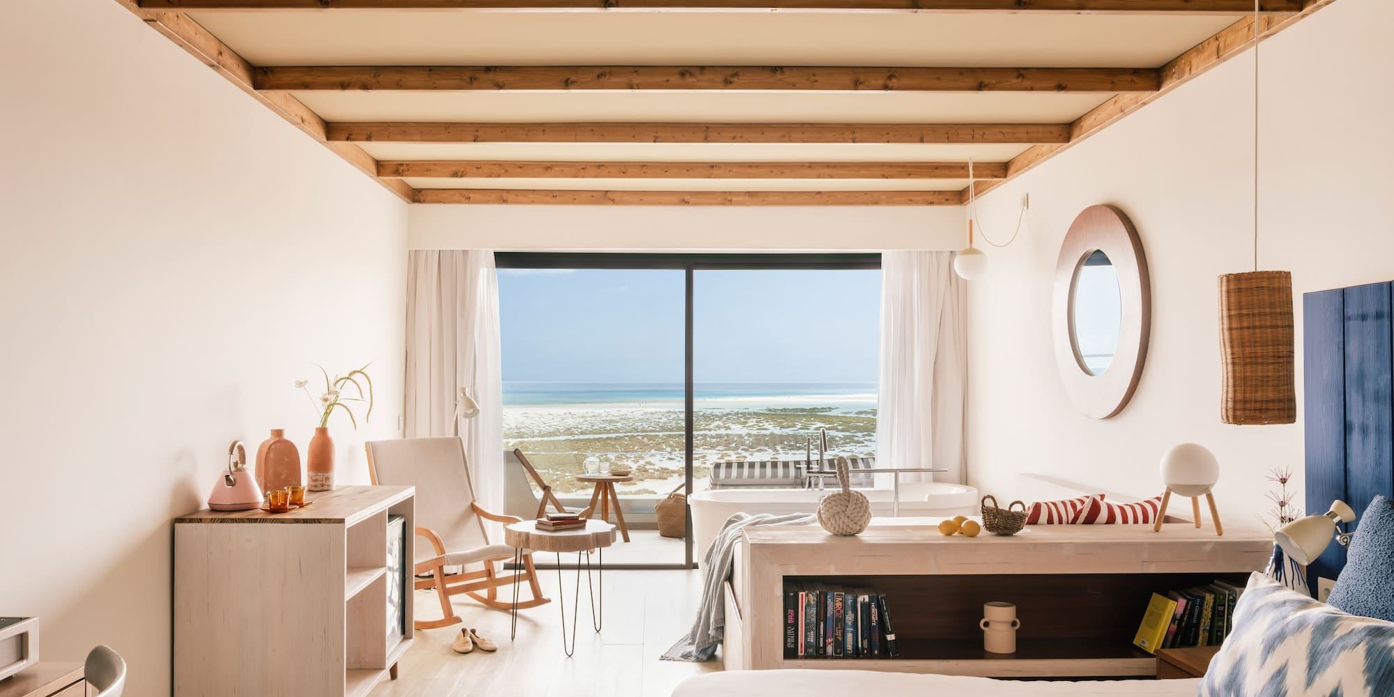 Beachfront luxury bedroom with ocean view, wooden beams, and modern decor.