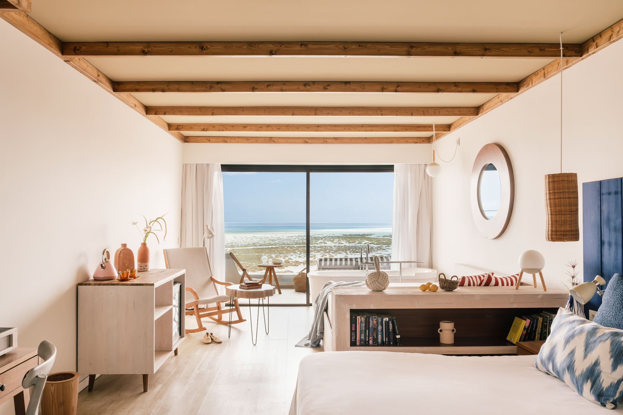 Luminosa suite moderna con vista panorámica al mar, vigas de madera y bañera.