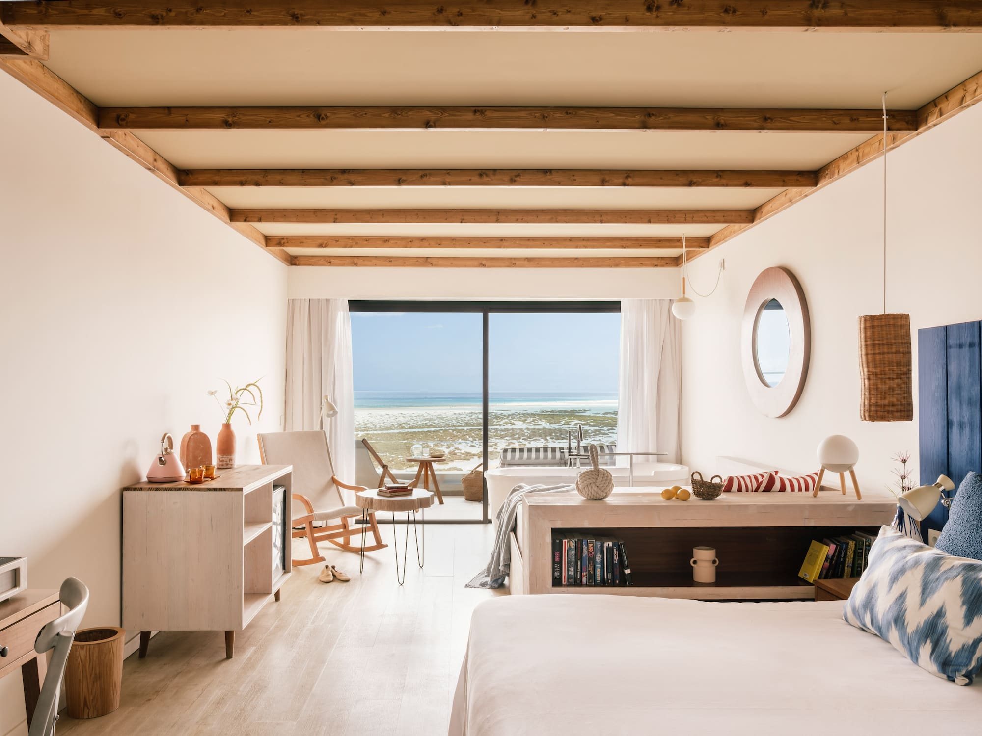 Beachfront luxury bedroom with ocean view, wooden beams, and modern decor.