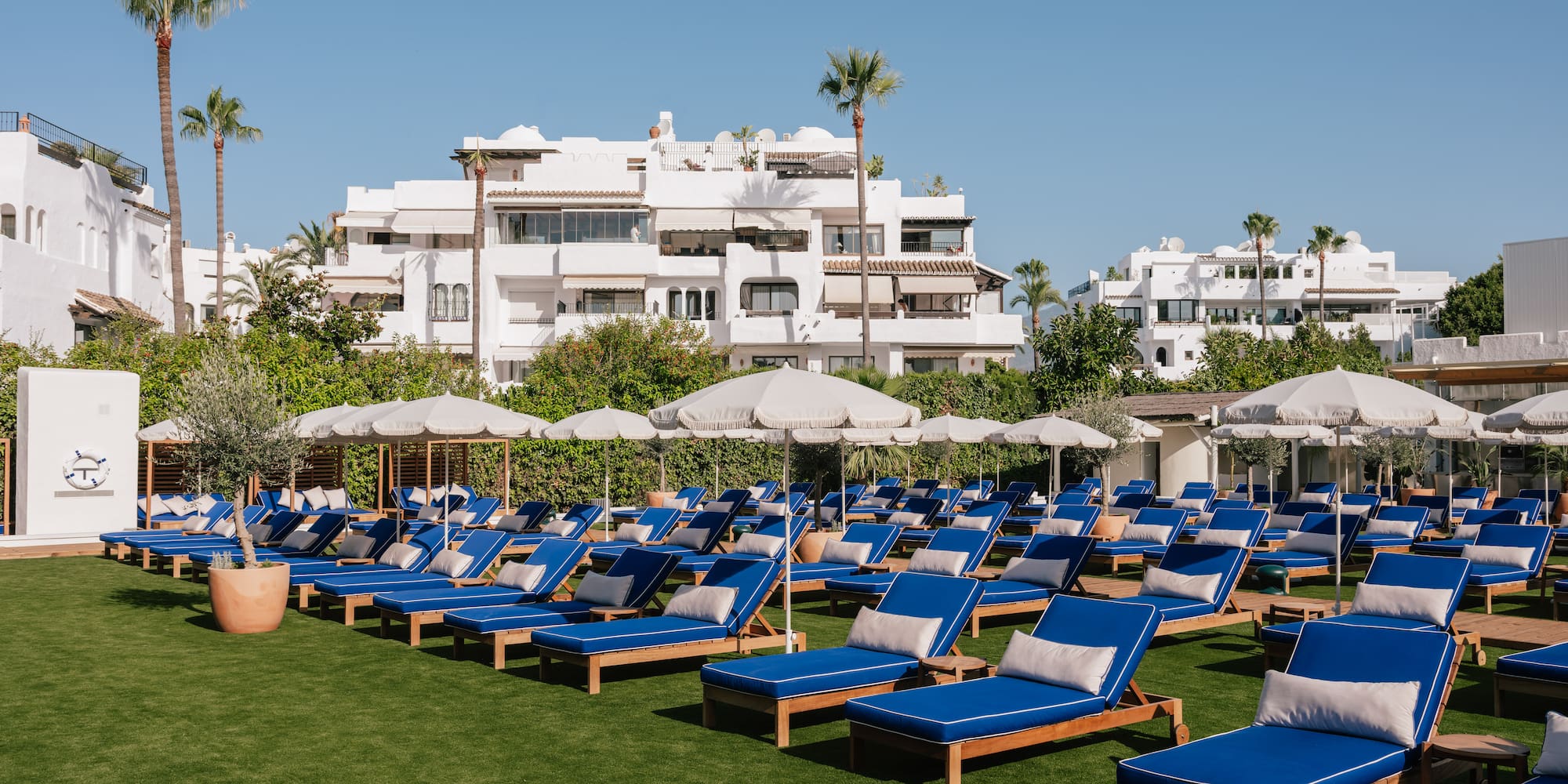 a group of lounge chairs and umbrellas on a lawn