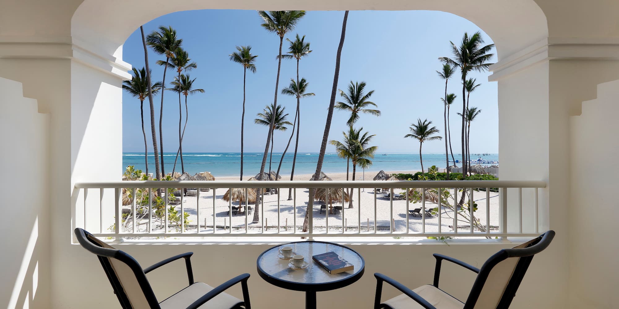 a balcony with a table and chairs overlooking a beach