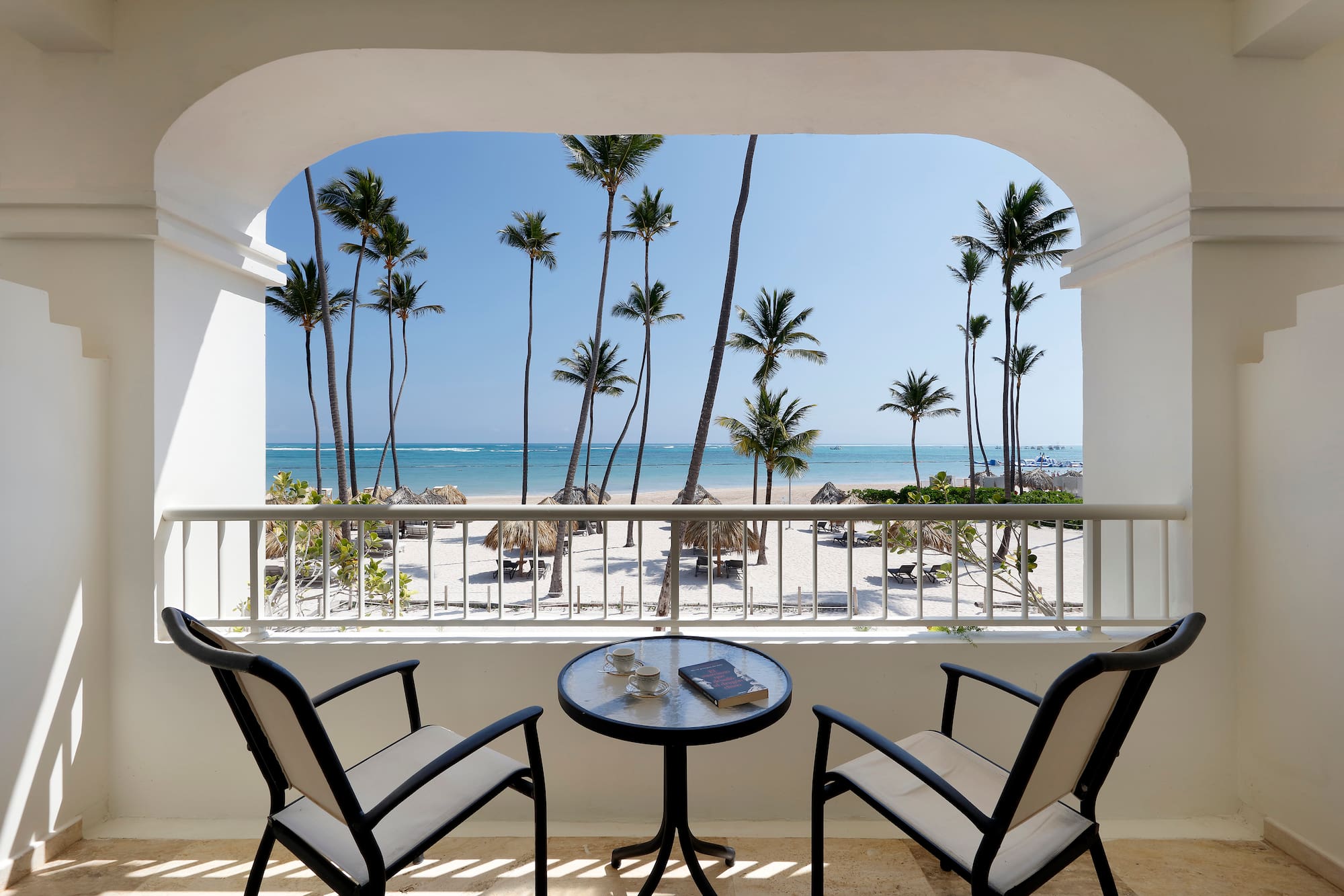 a balcony with a table and chairs overlooking a beach