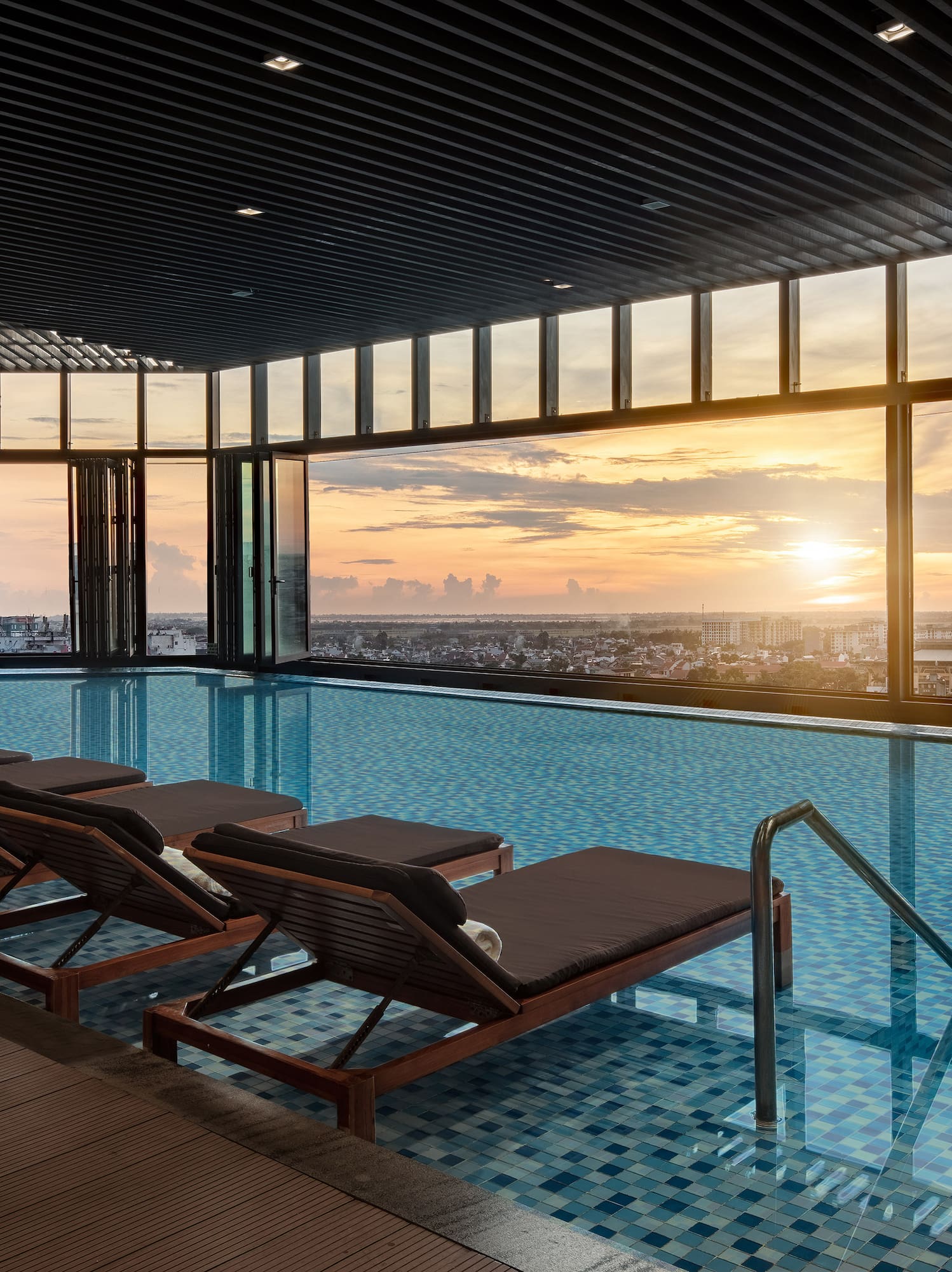 a pool with chairs and a view of the city