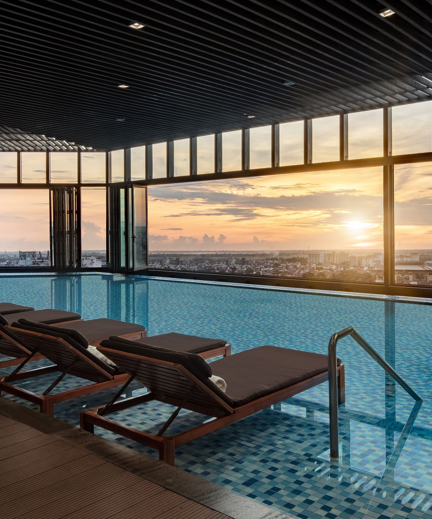 a pool with chairs and a view of the city