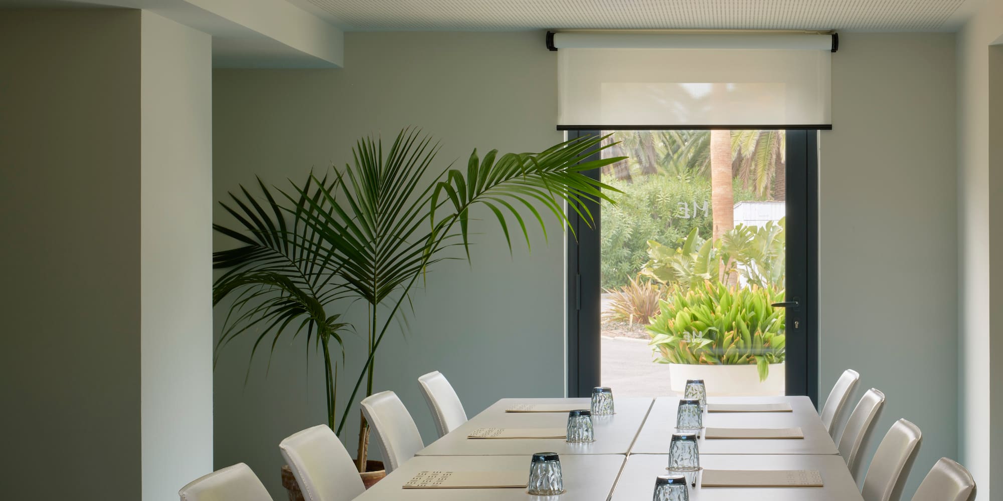 a long table with white chairs and glasses on it