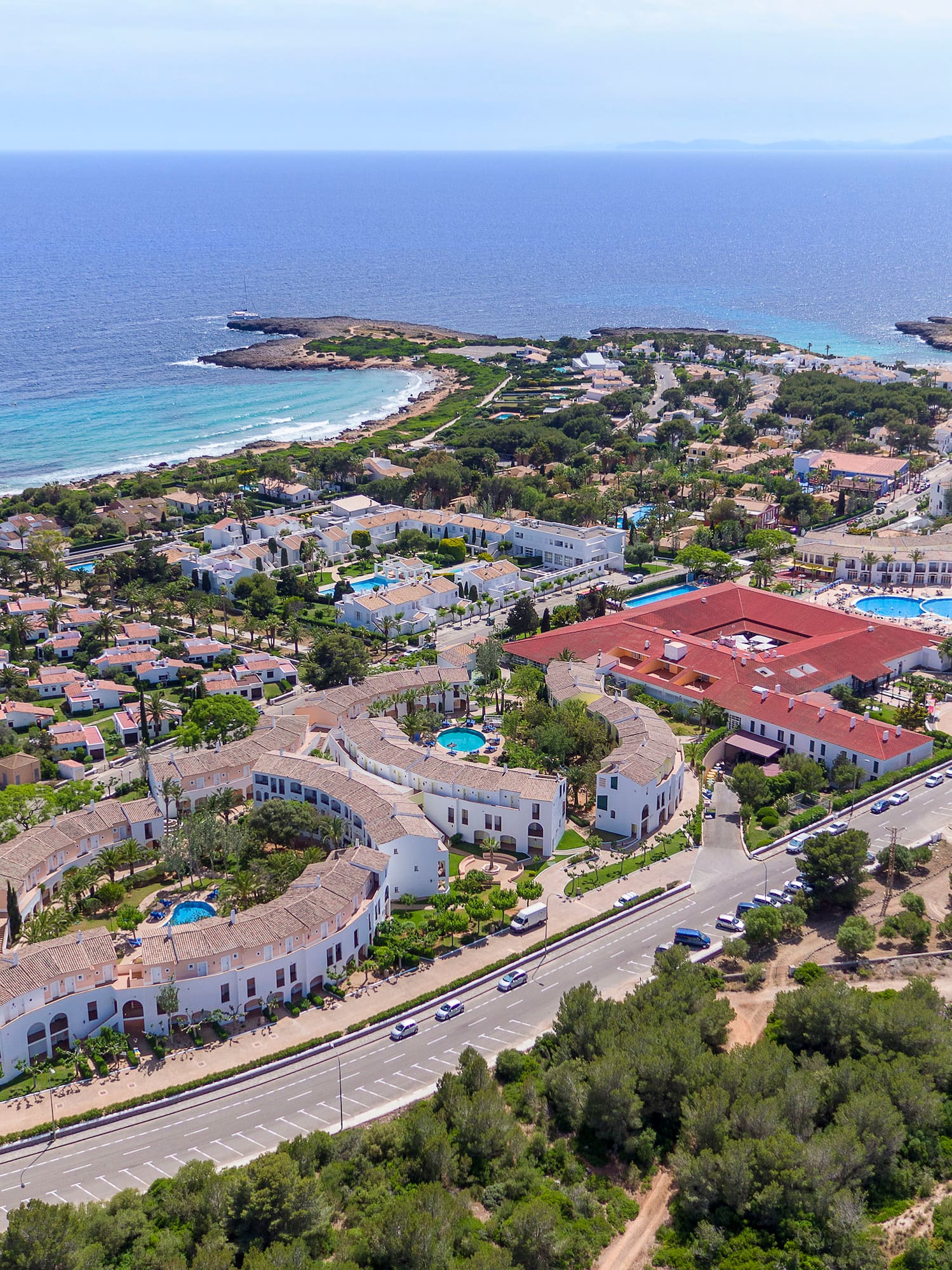Aerial view of Mallorca beach resort with hotels, pools, and turquoise sea.