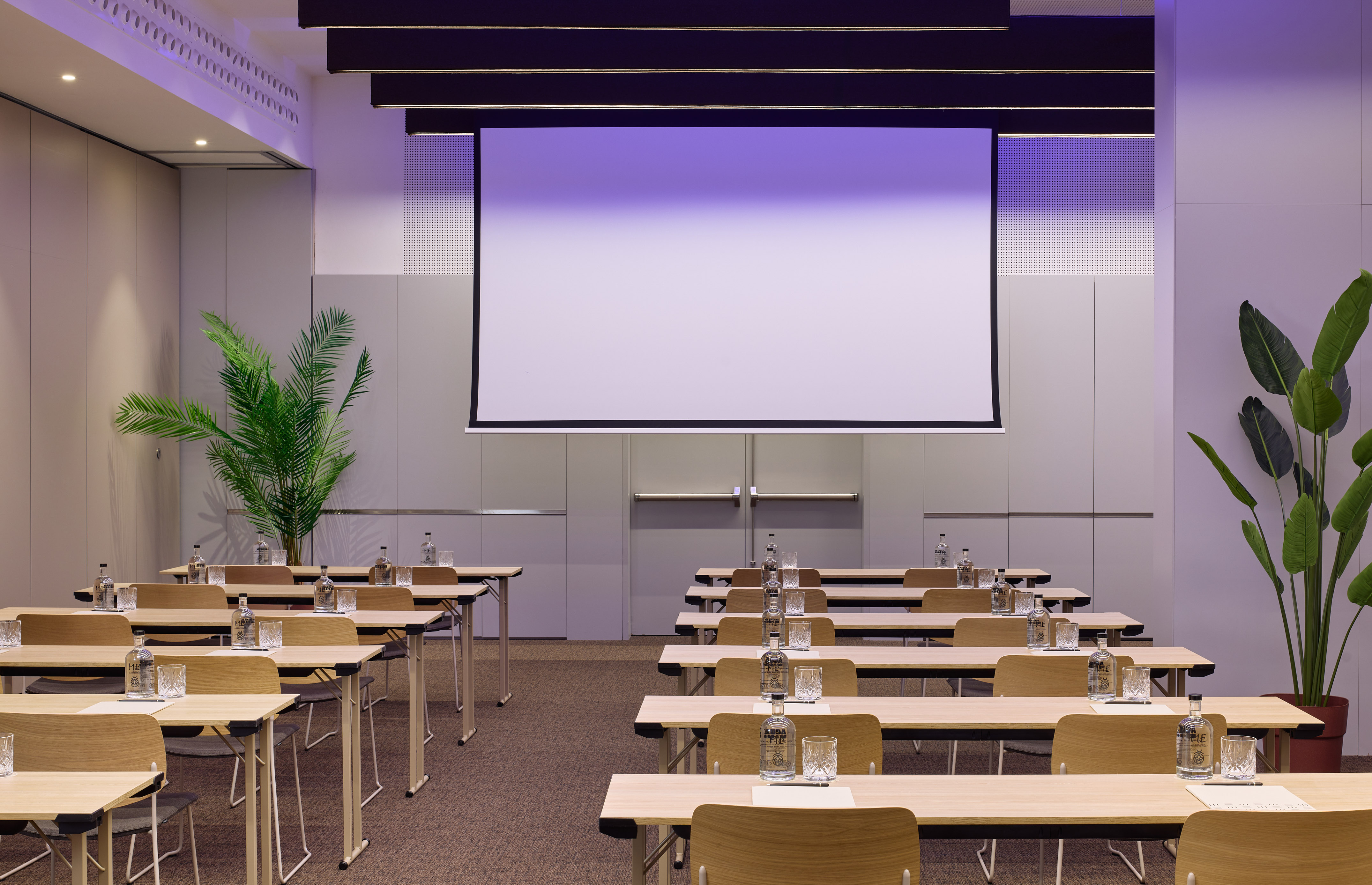 Modern meeting room set up for corporate events with screen and tables.