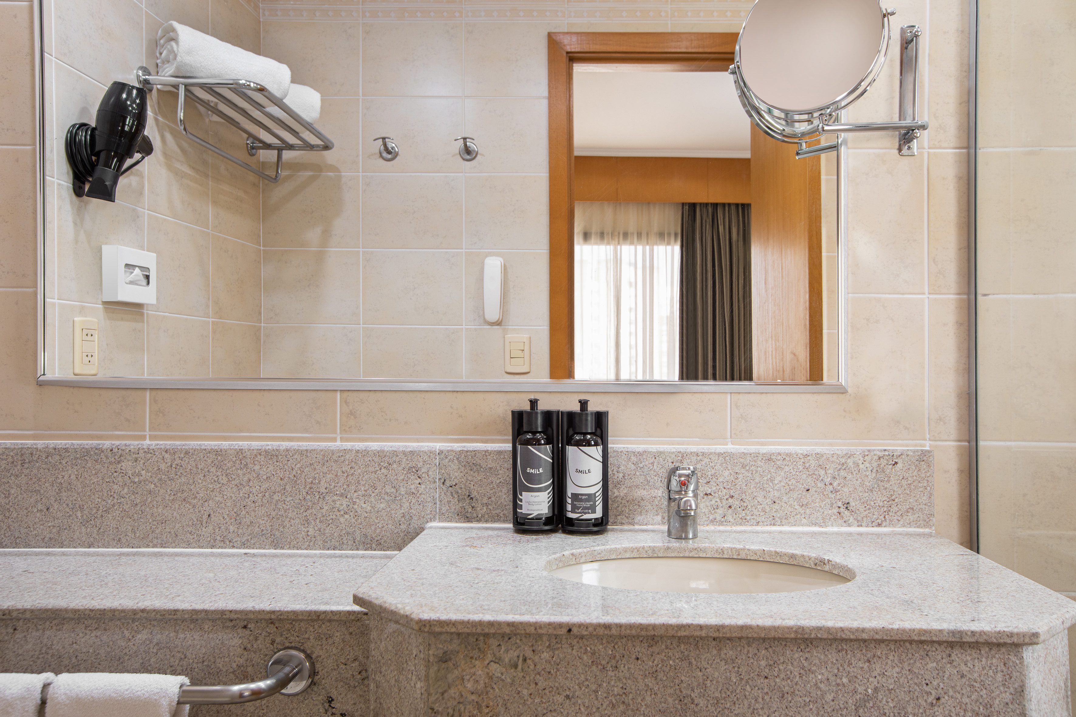 Hotel bathroom granite vanity, sink, mirror, toiletries, towels, hair dryer.