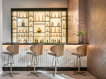 a bar with chairs and bottles on shelves