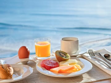 a plate of fruit and a egg on a table with a body of water