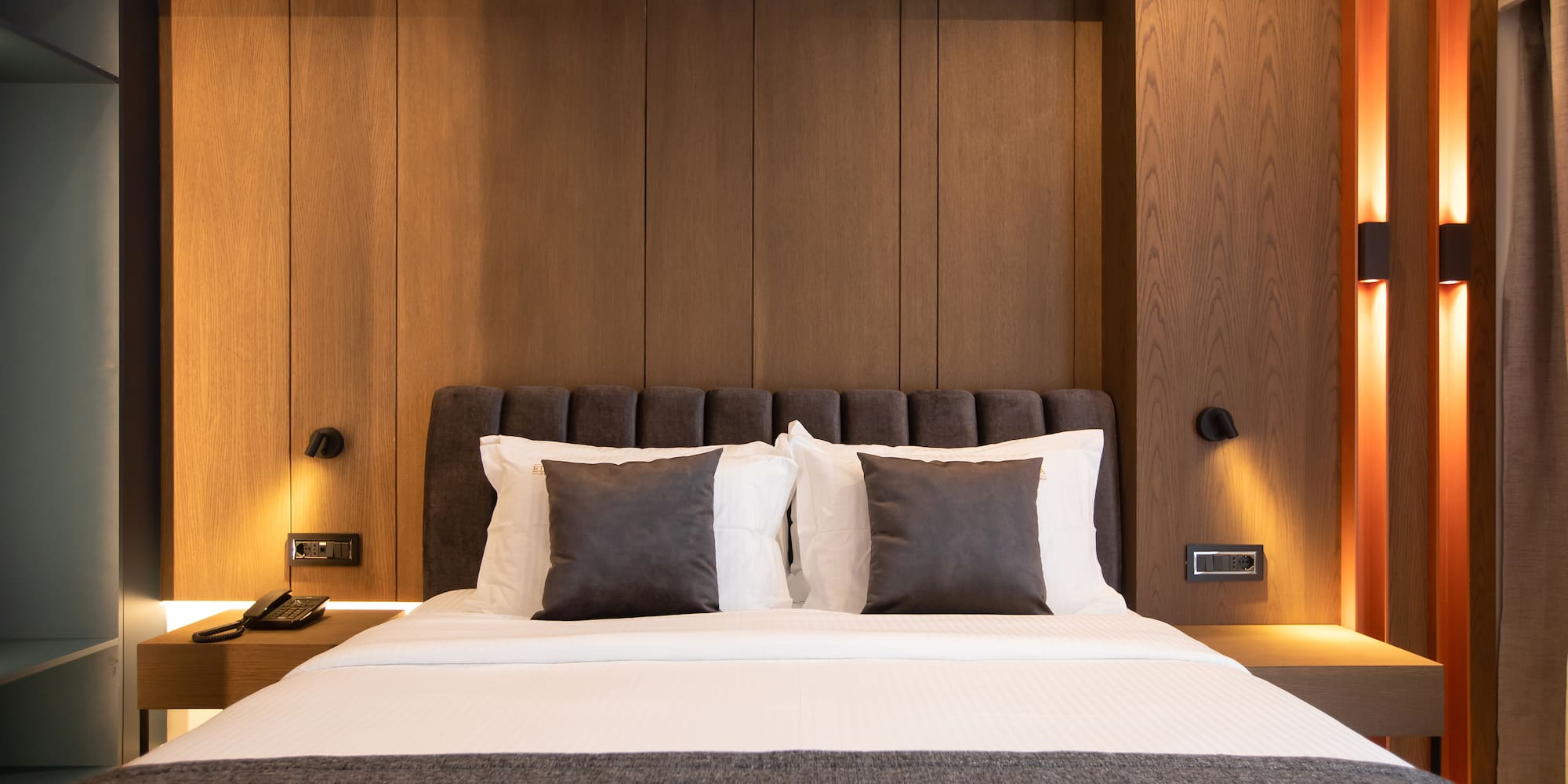 a bed with pillows and a lamp on the wall