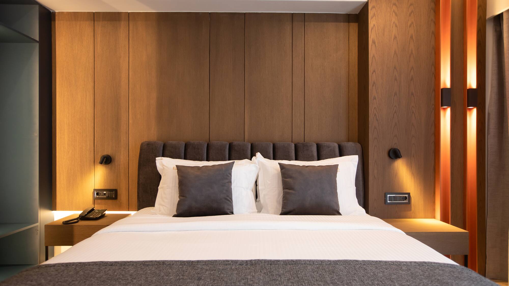 a bed with pillows and a lamp on the wall