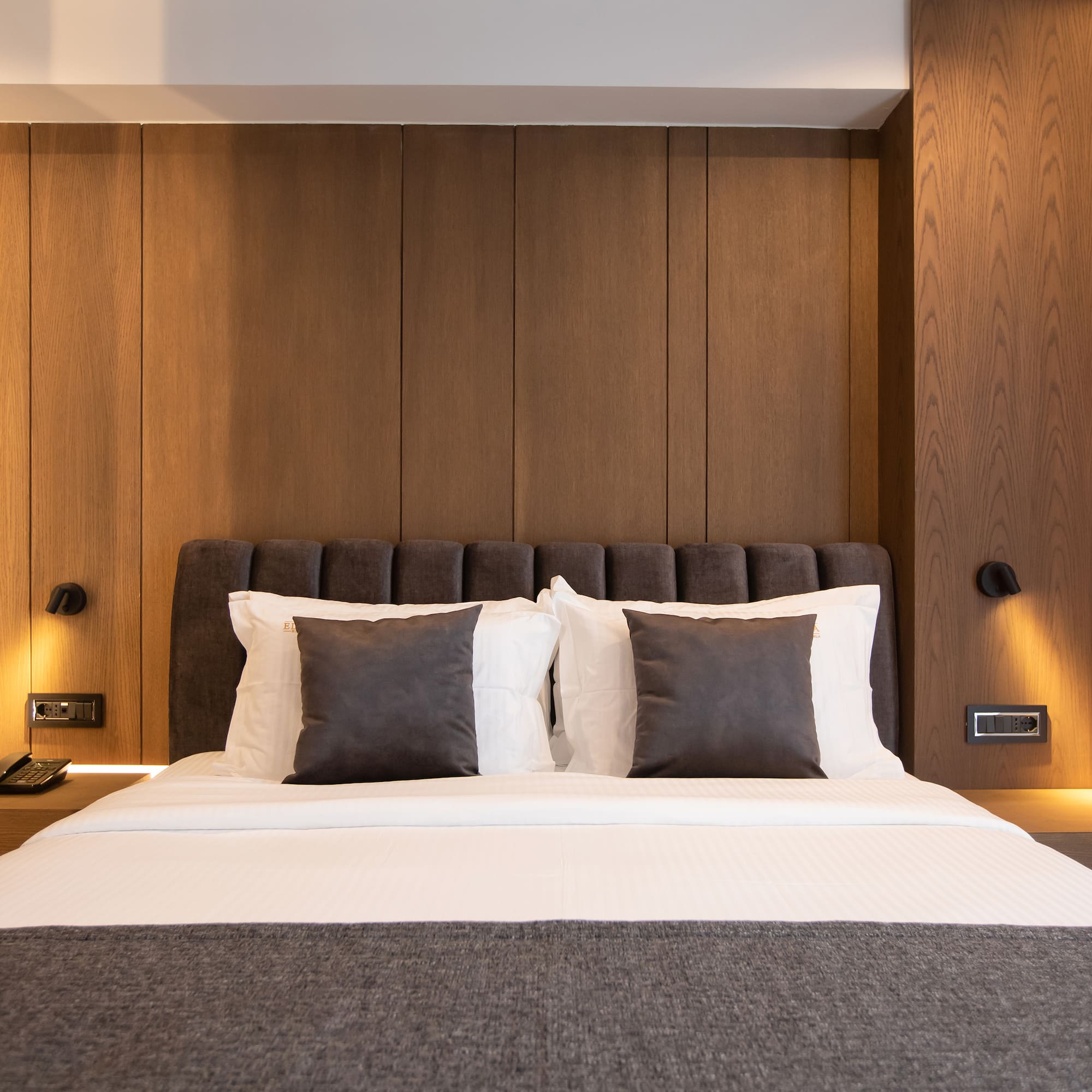 a bed with pillows and a lamp on the wall