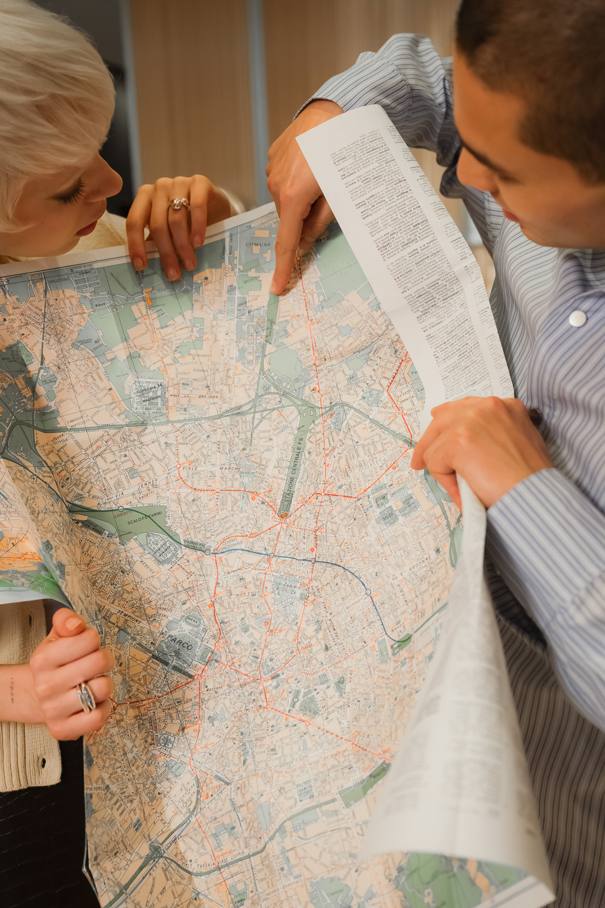 Pareja señalando una ruta en un mapa de ciudad, planificando su viaje.
