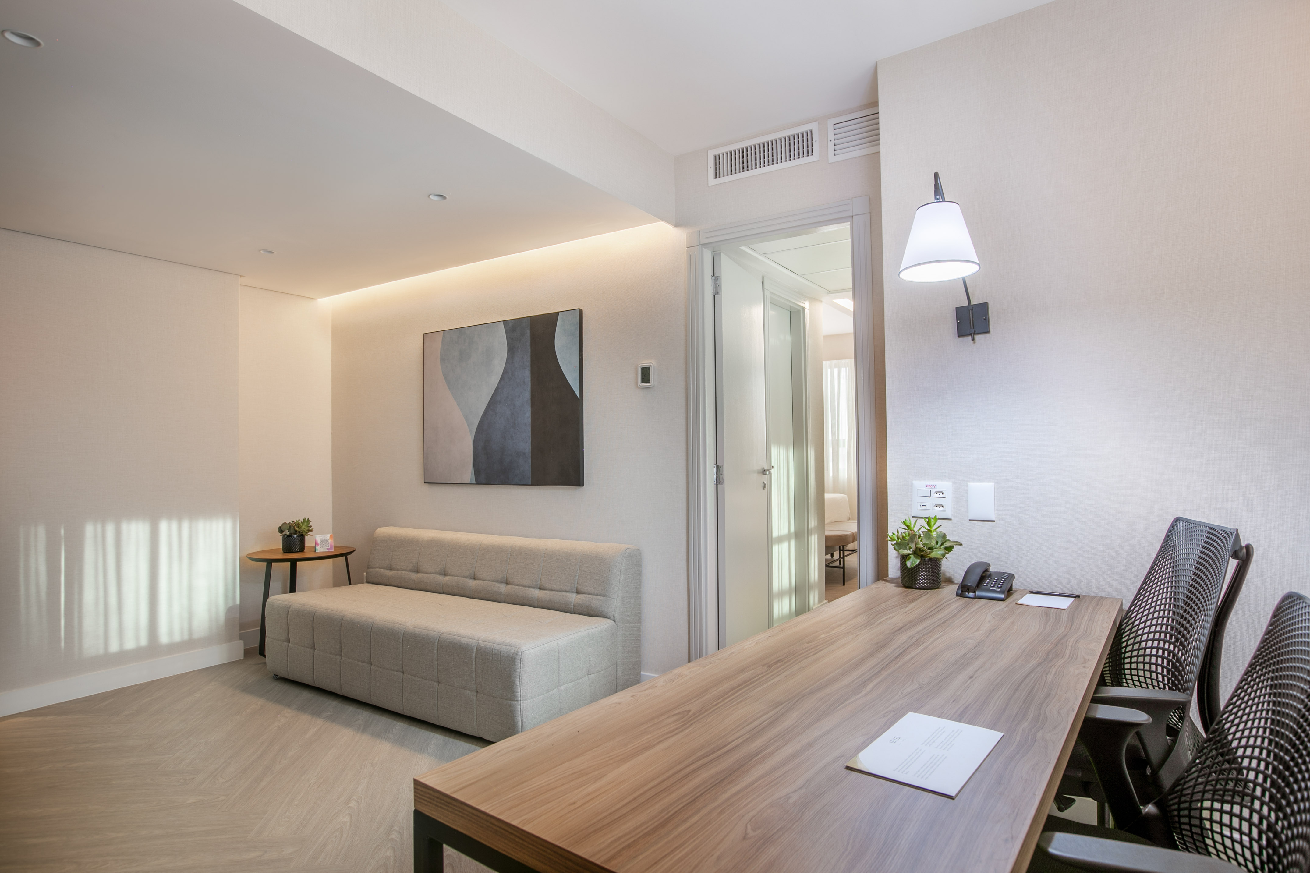 Minimalist office suite with wooden desk, chairs, sofa, and abstract art.