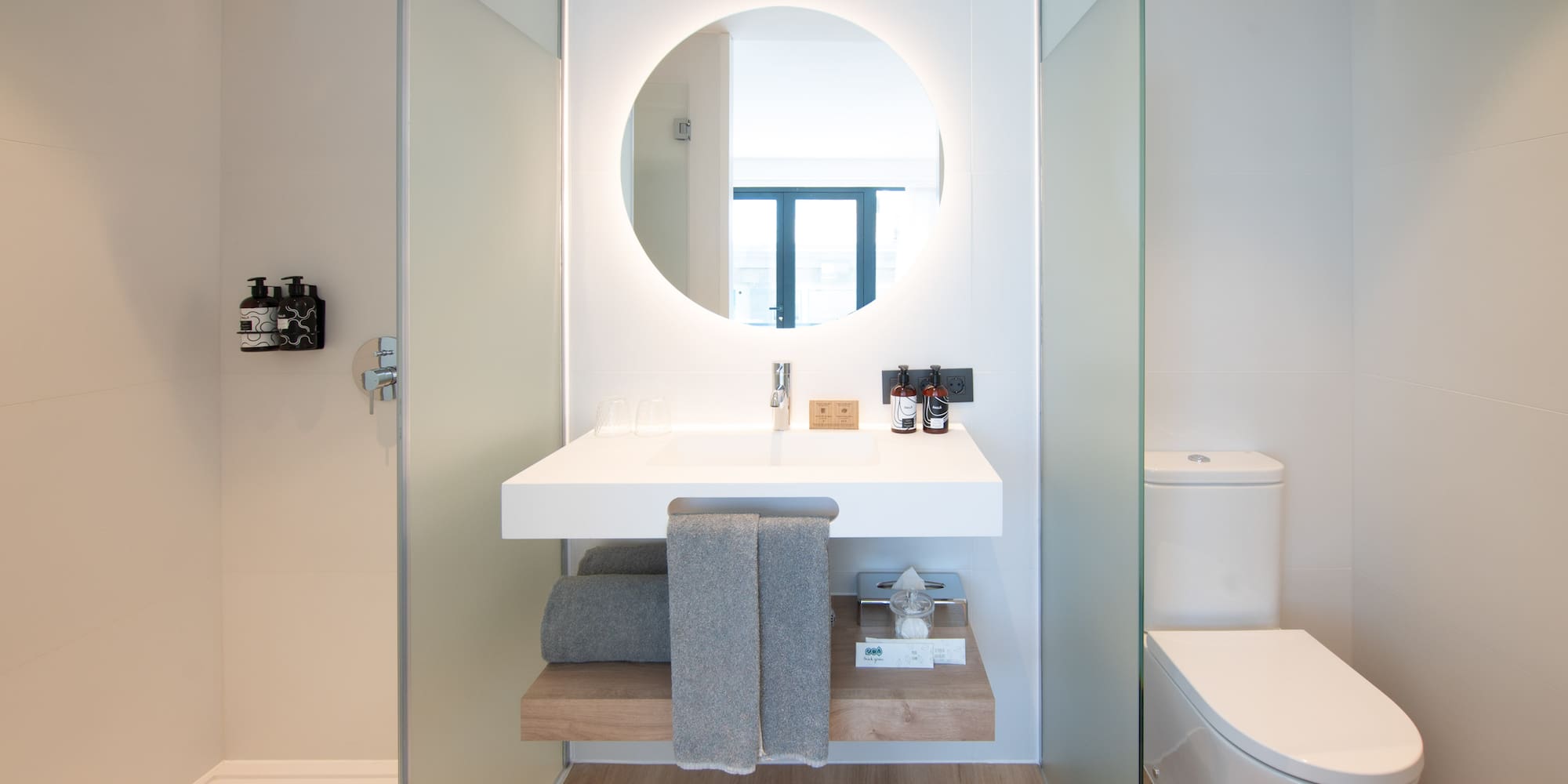 a bathroom with a round mirror and a toilet