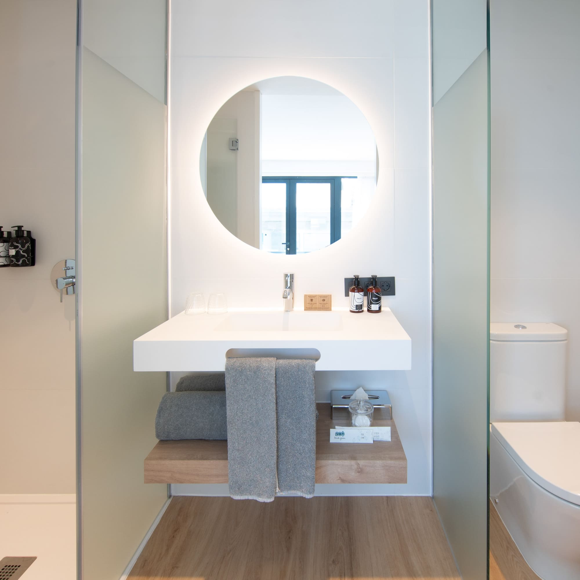 a bathroom with a round mirror and a toilet