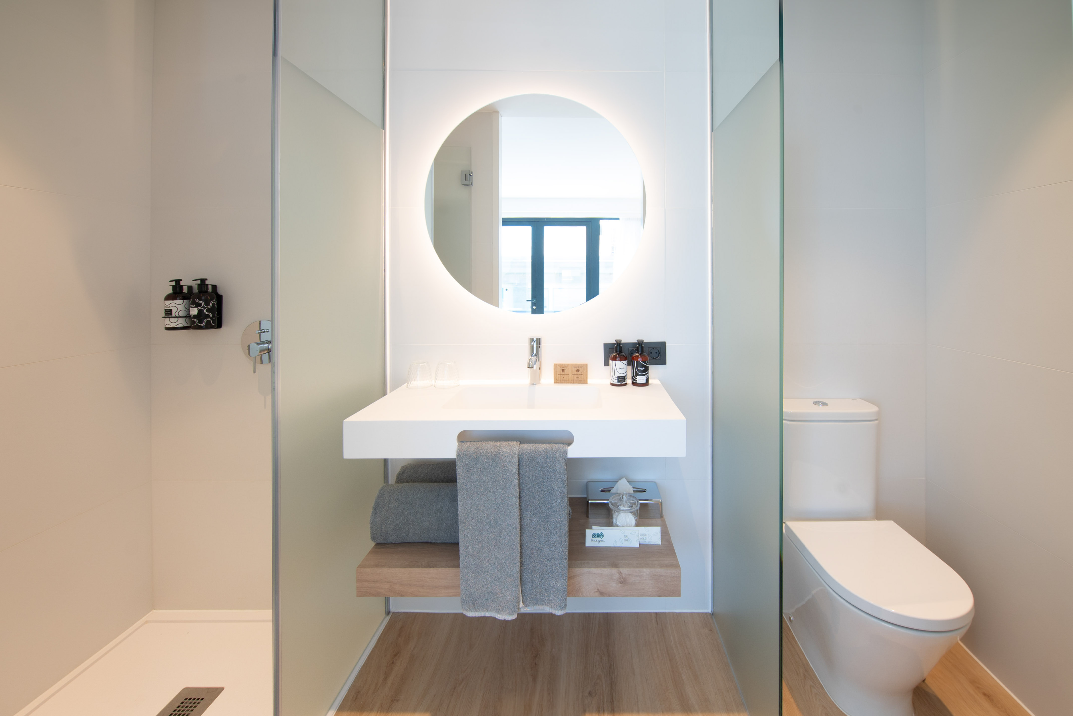 a bathroom with a round mirror and a toilet