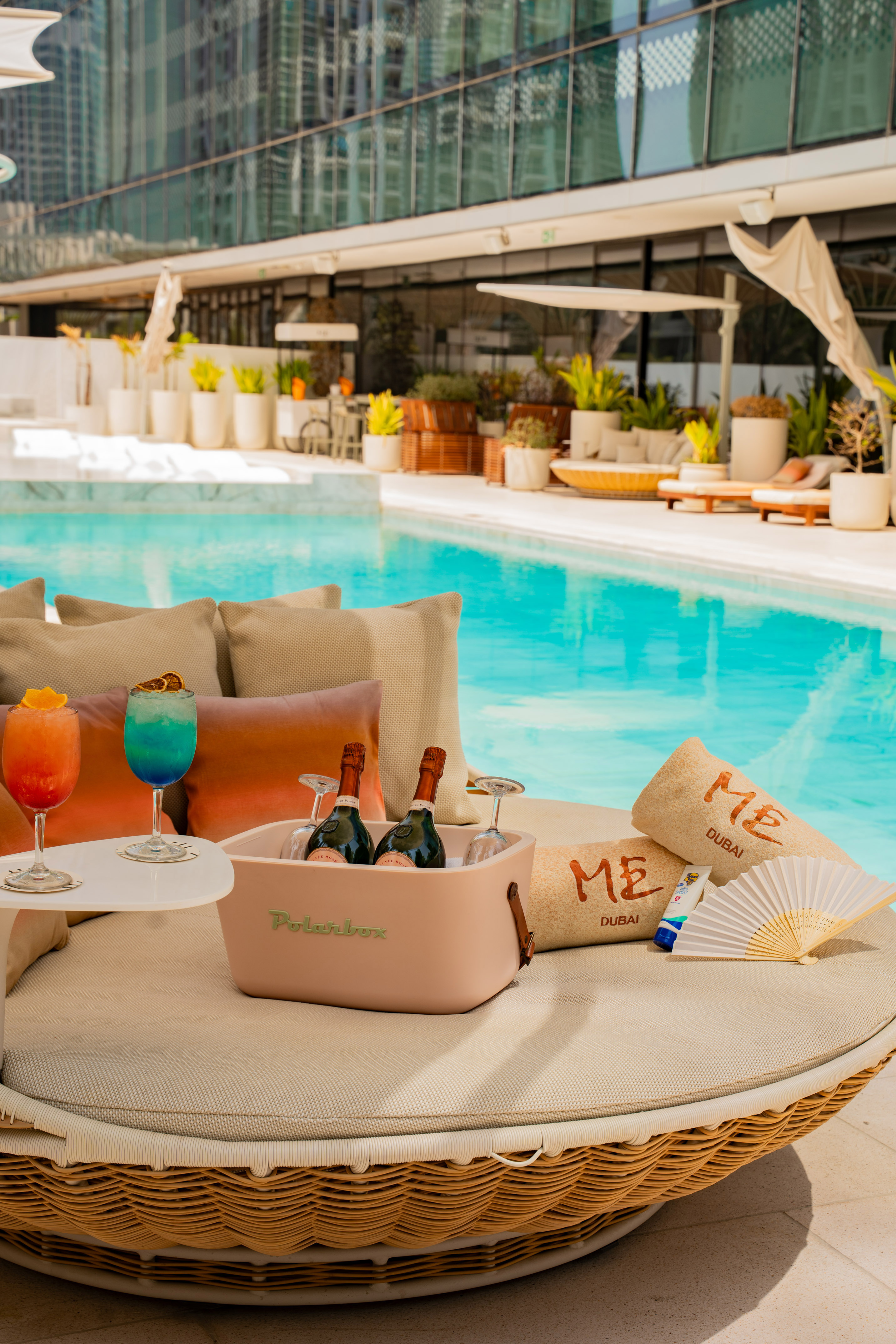 Dubai luxury poolside: cocktails, champagne cooler, ME towels on a daybed.