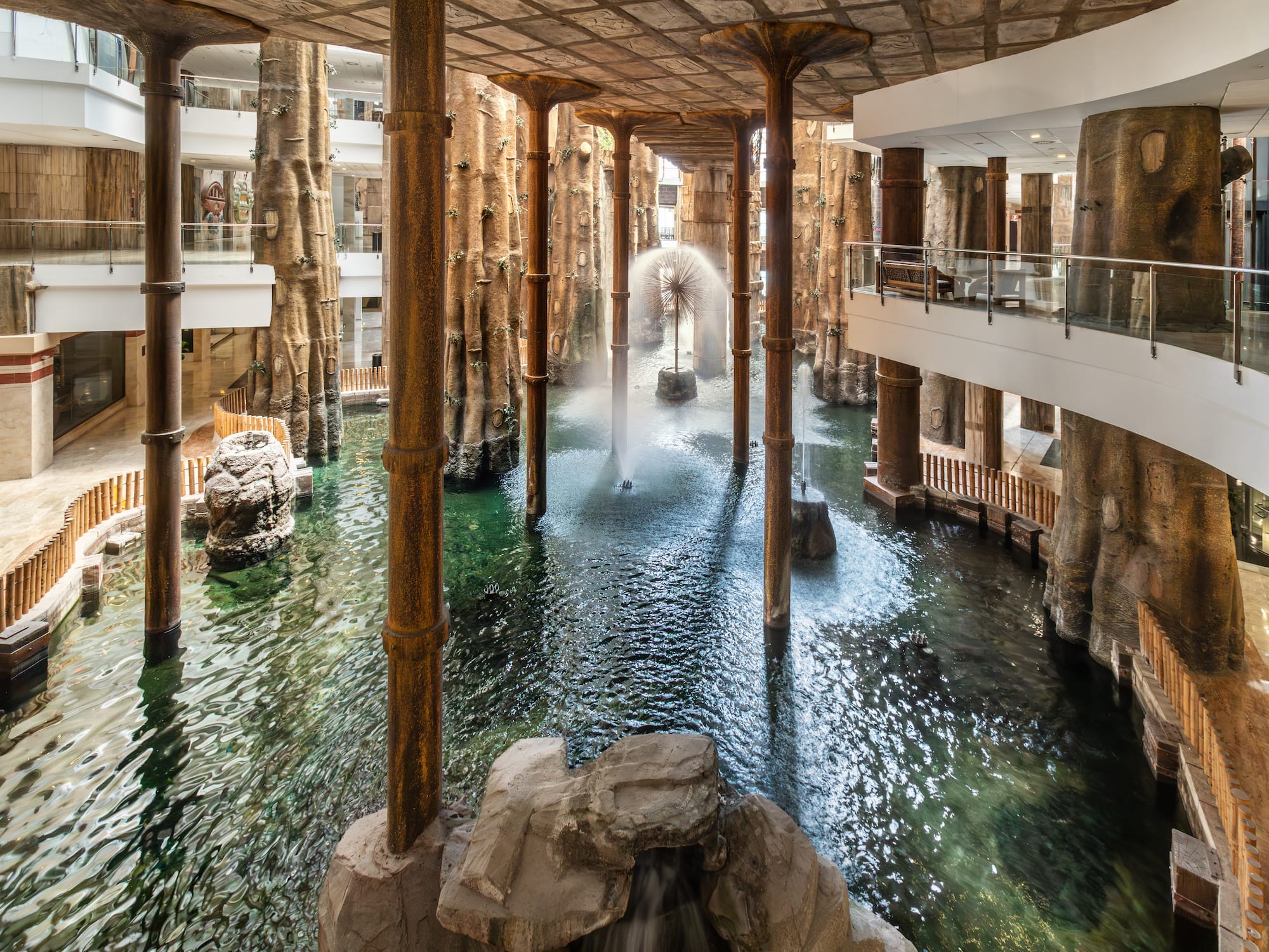 Indoor atrium with water feature, fountains, and distinctive tree columns.