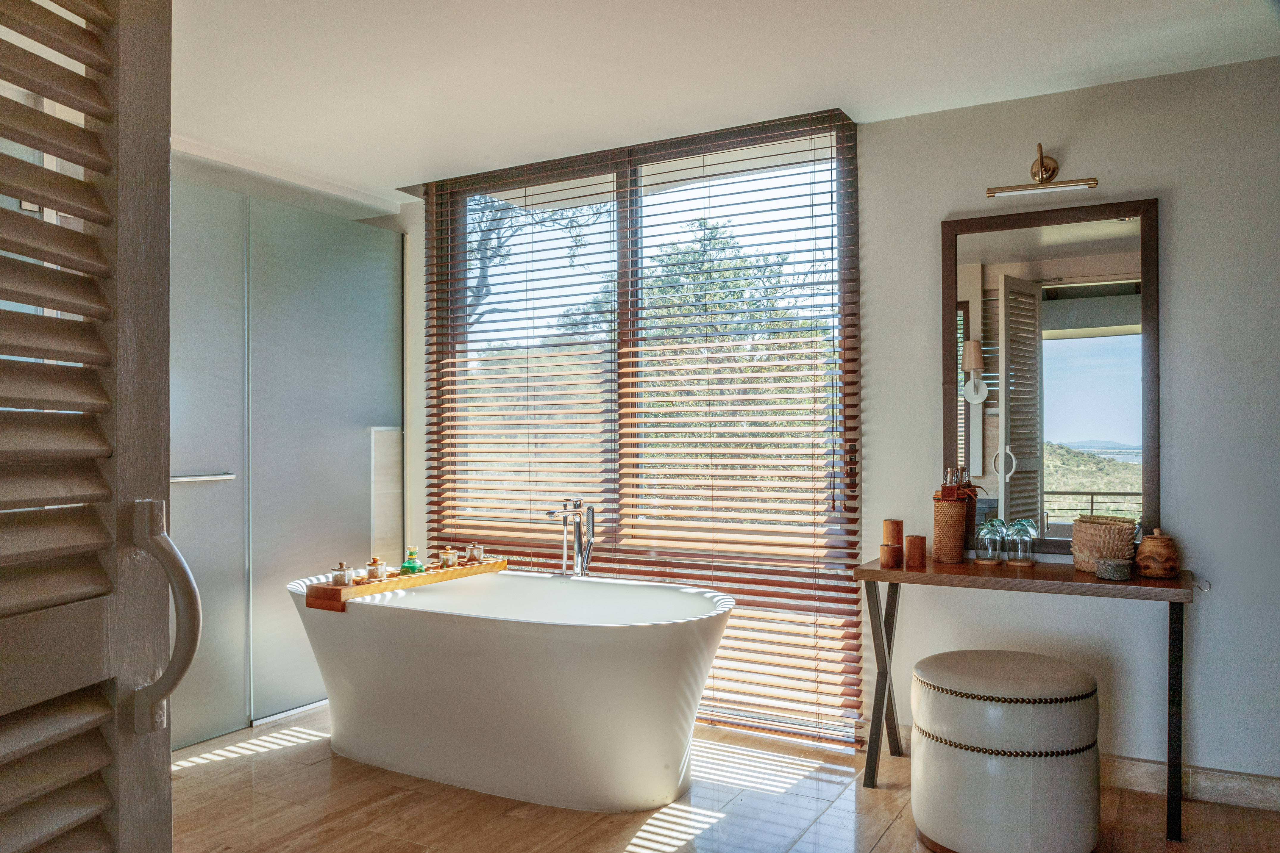 Luxurious bathroom with freestanding tub, window blinds, and scenic outdoor view.