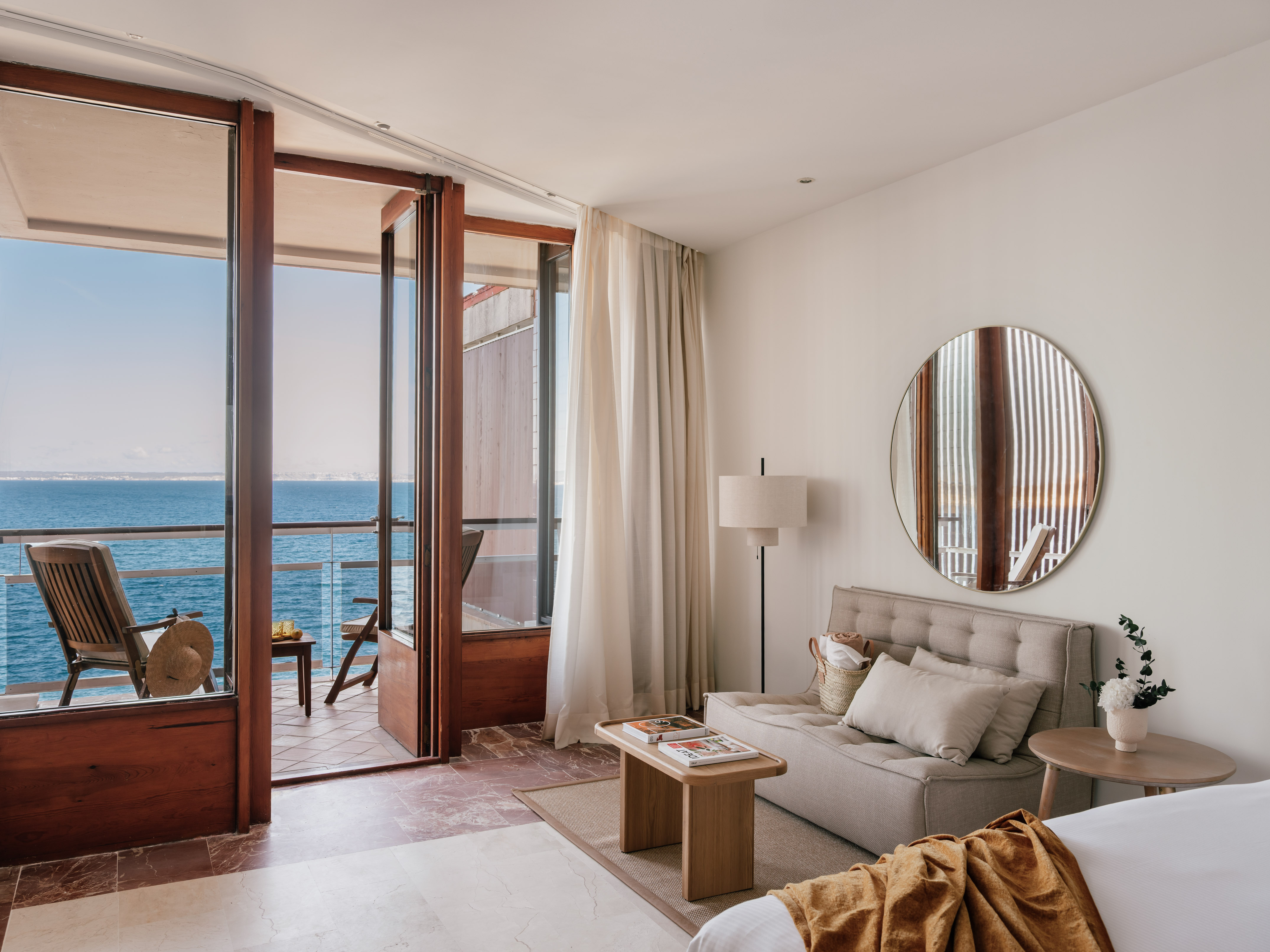 Oceanfront hotel room with modern interior, balcony, sofa, and sea view.