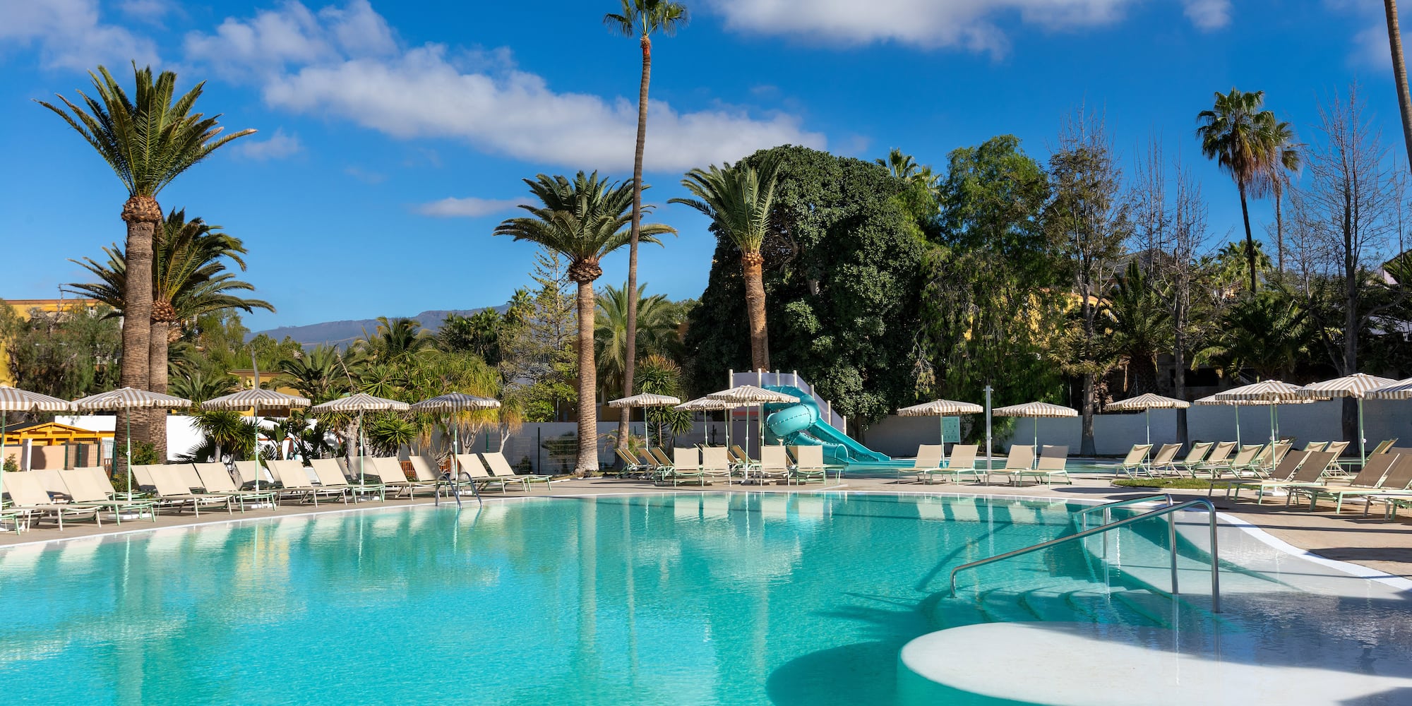 a pool with a slide and chairs
