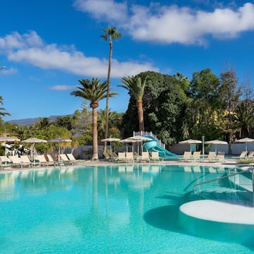 a pool with a slide and chairs
