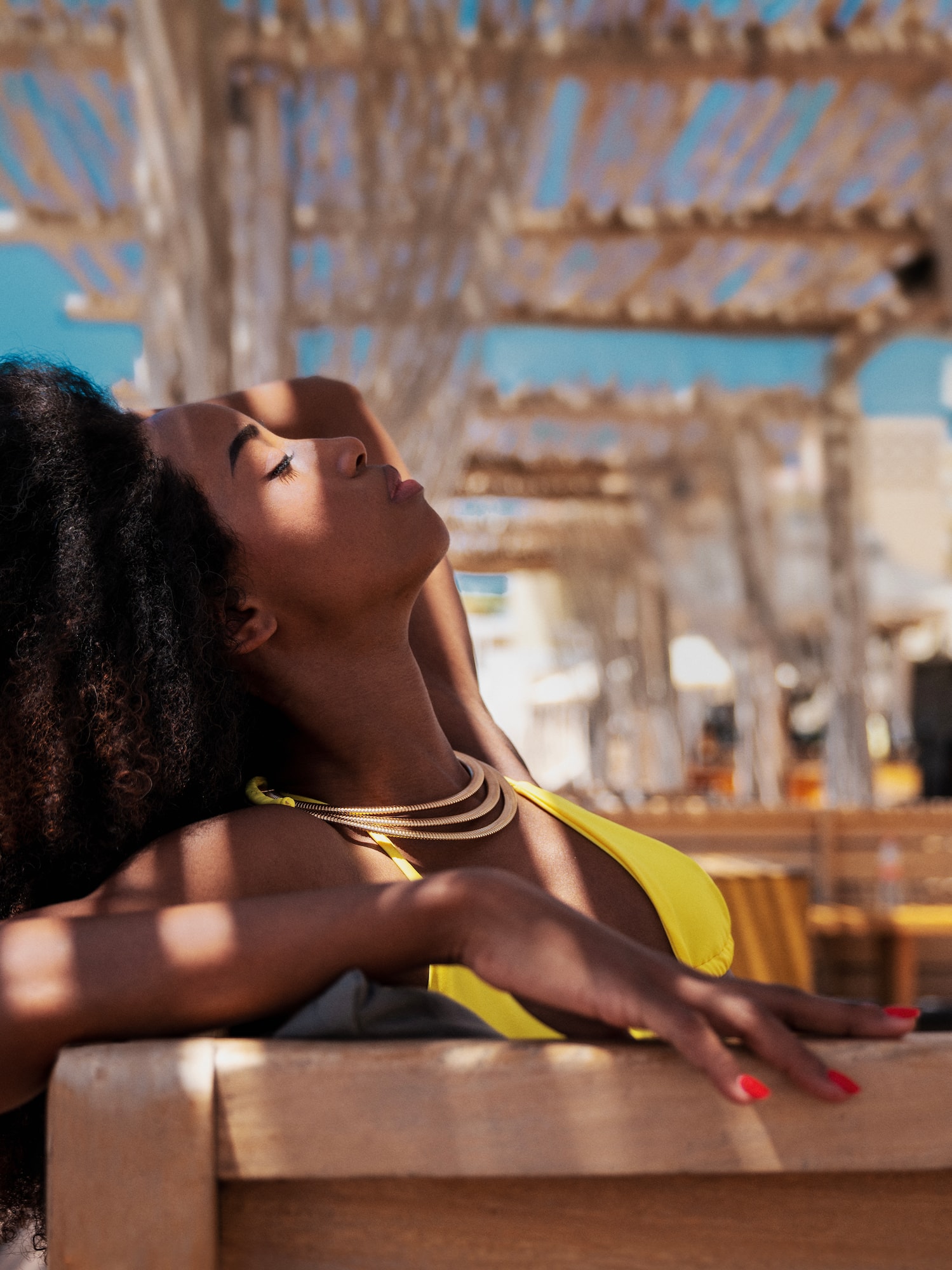 a woman in a yellow garment leaning on a bench