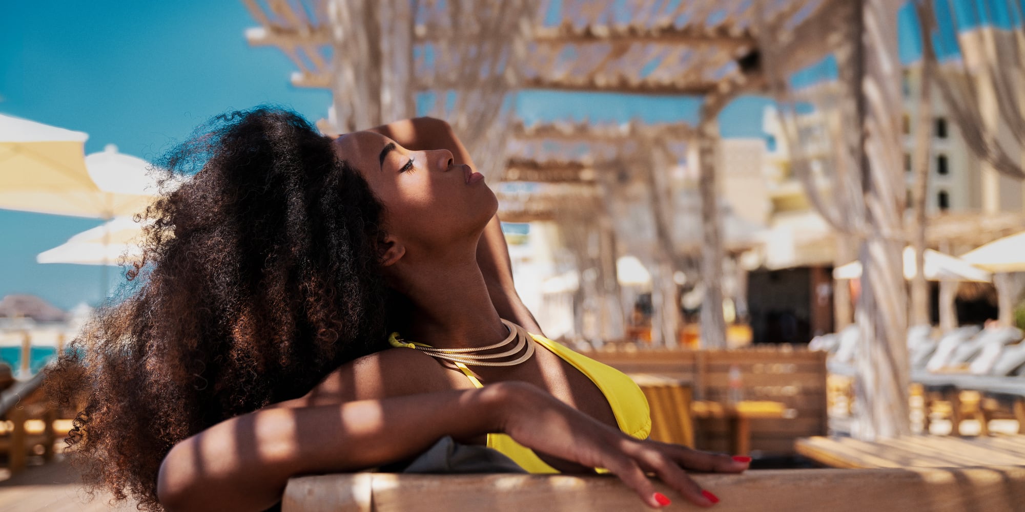 a woman in a yellow garment leaning on a bench