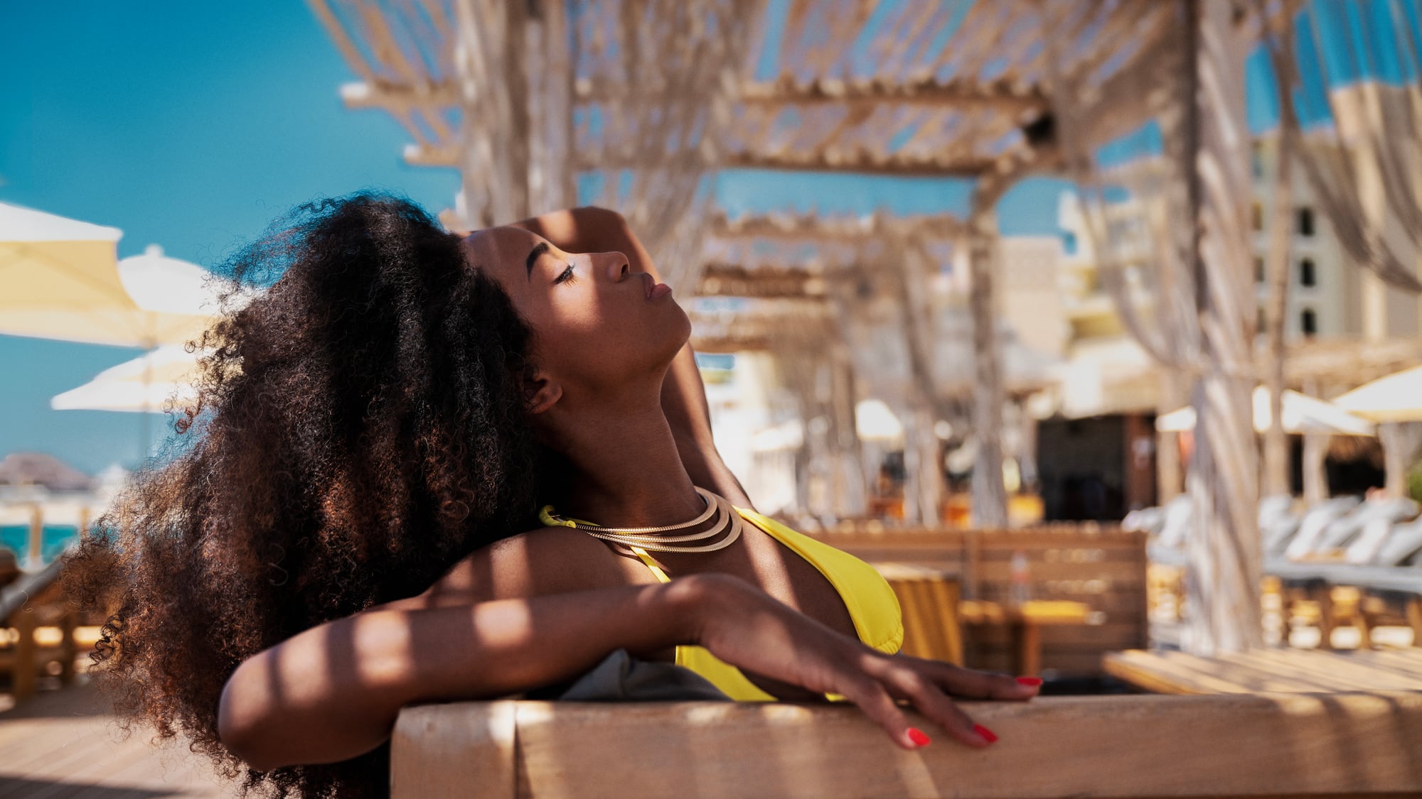 a woman in a yellow garment leaning on a bench