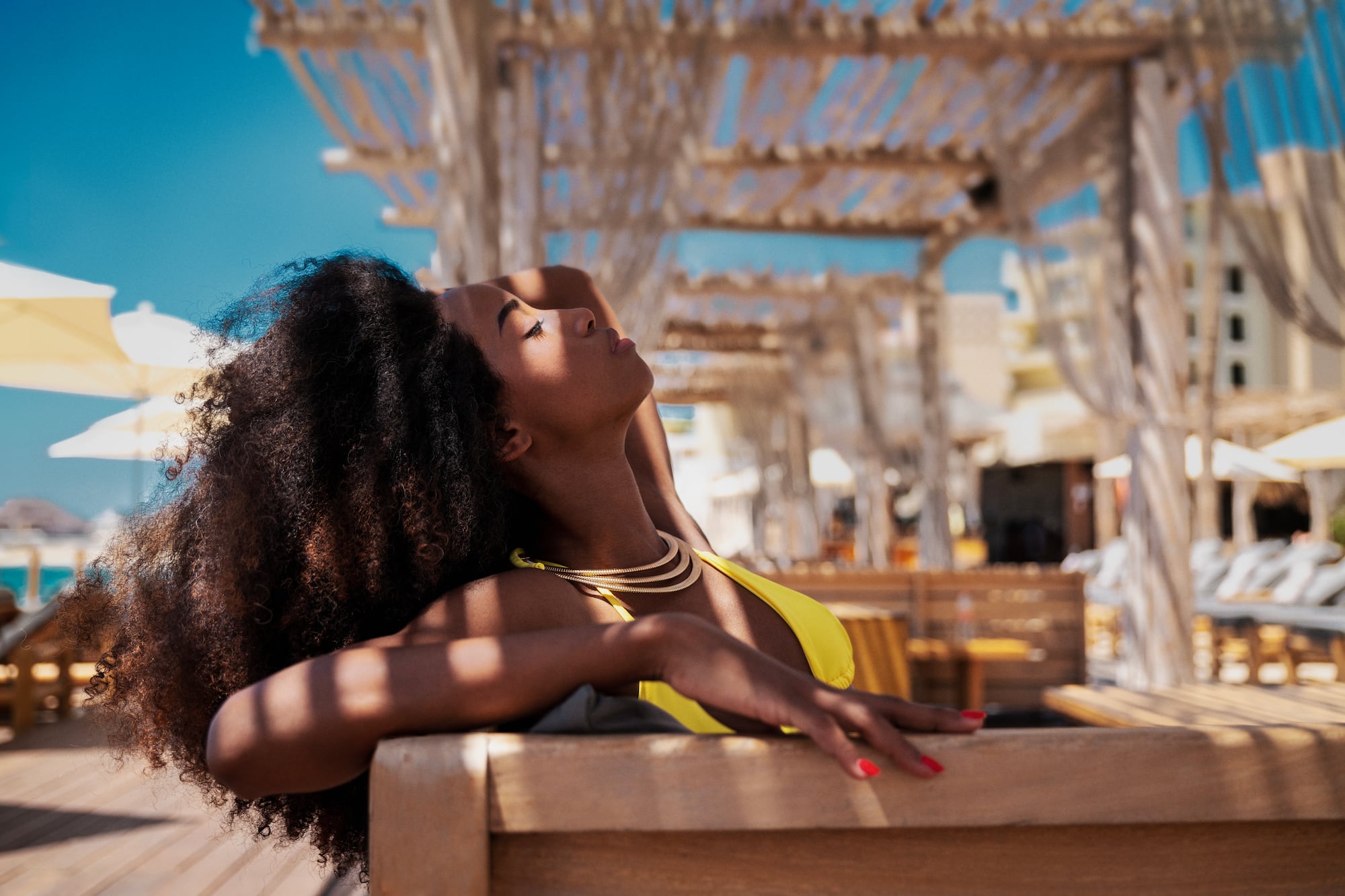 a woman in a yellow garment leaning on a bench