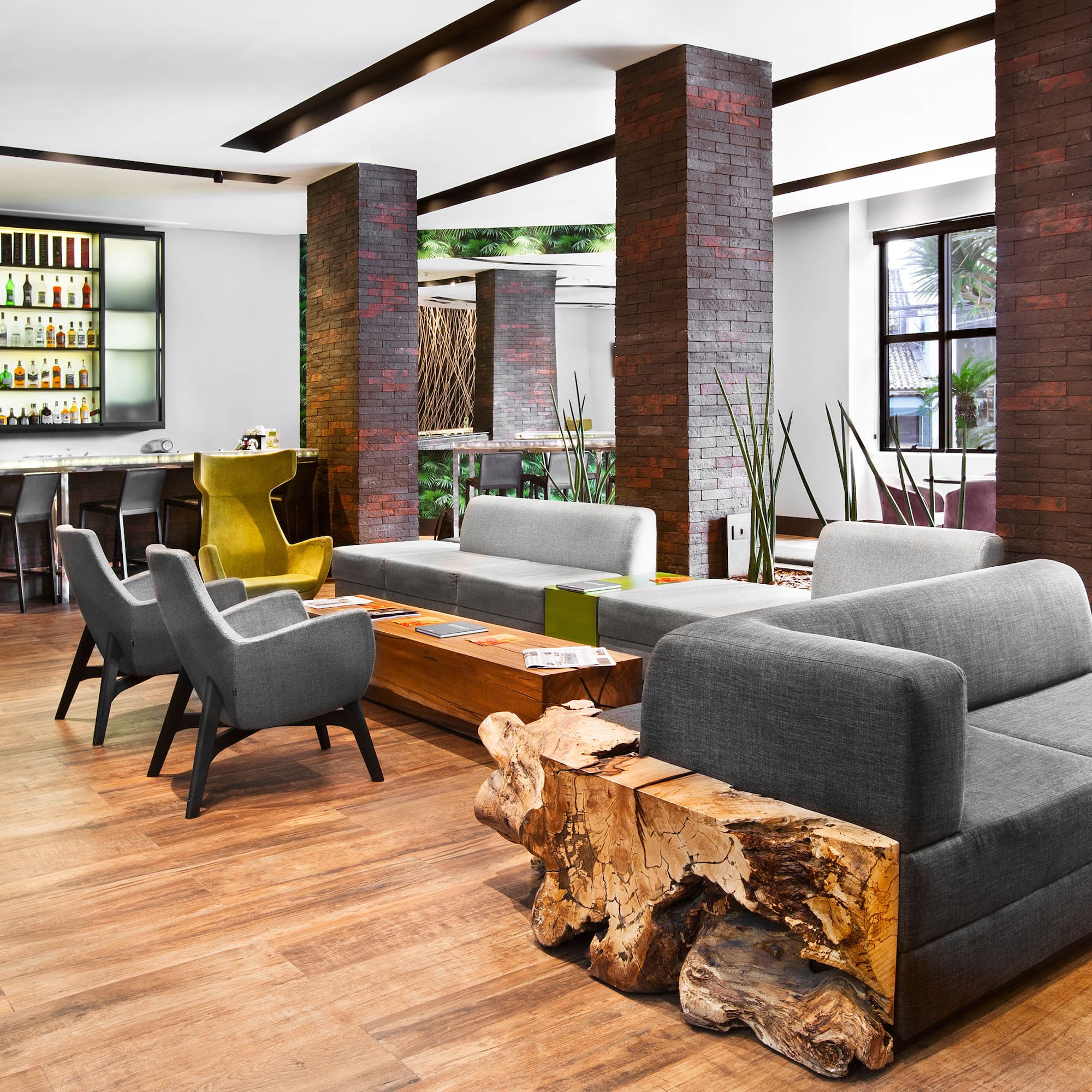 Modern hotel bar and lounge with modular seating, wood tables, and brick pillars. - Meliá Ibirapuera, São Paulo
