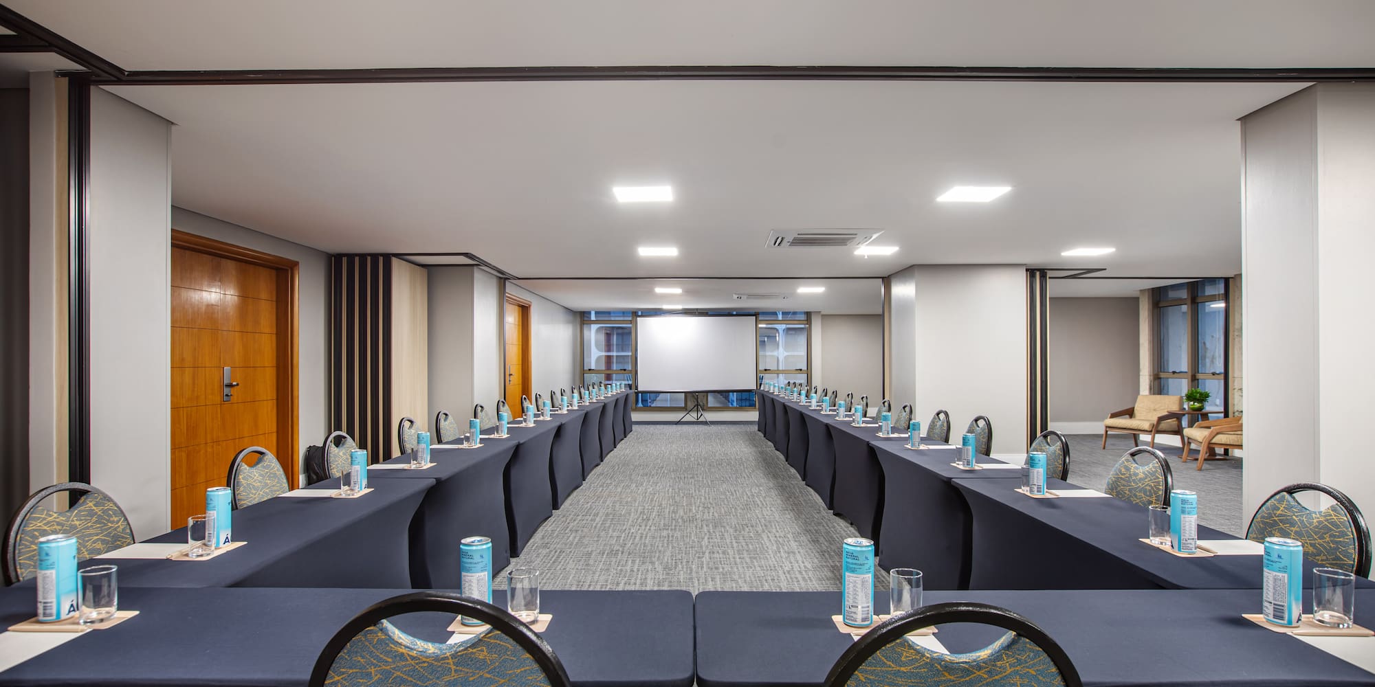 U-shaped conference room with projector screen and tables for meetings.