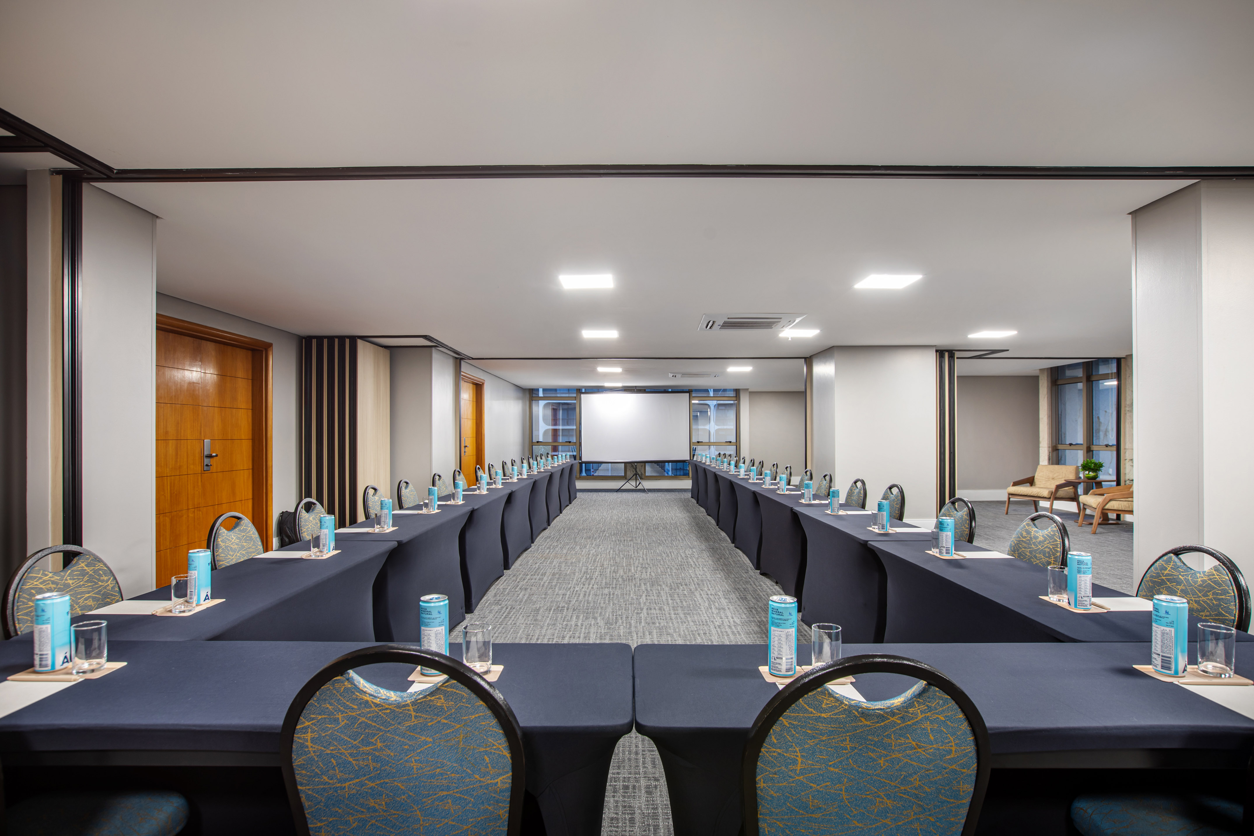 U-shaped conference room with projector screen and tables for meetings.